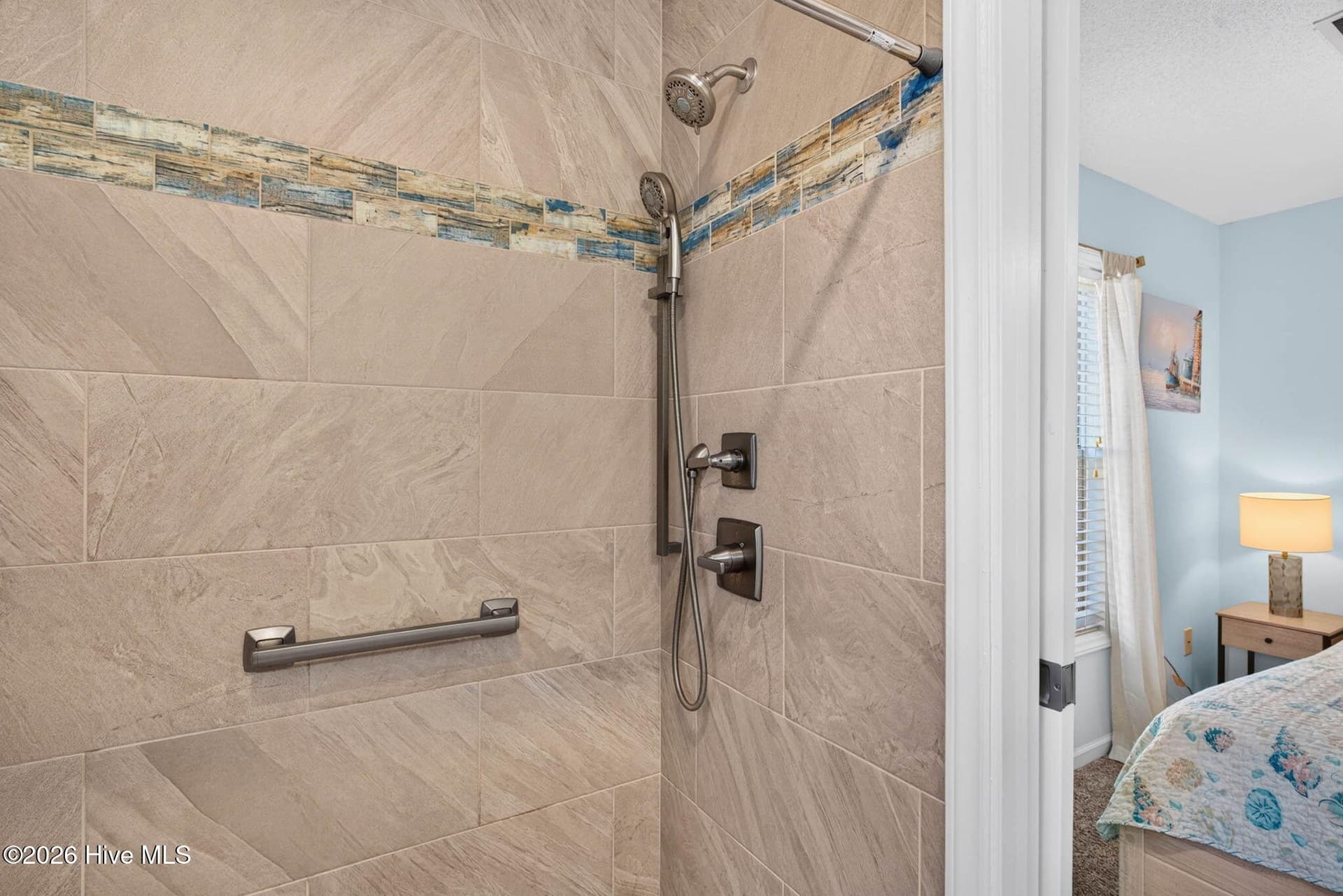 Custom tiled, low-threshold shower with grab bars adds both style and accessibility to the primary suite. - 1650 Frink Street SW, Ocean Isle Beach, NC 28469