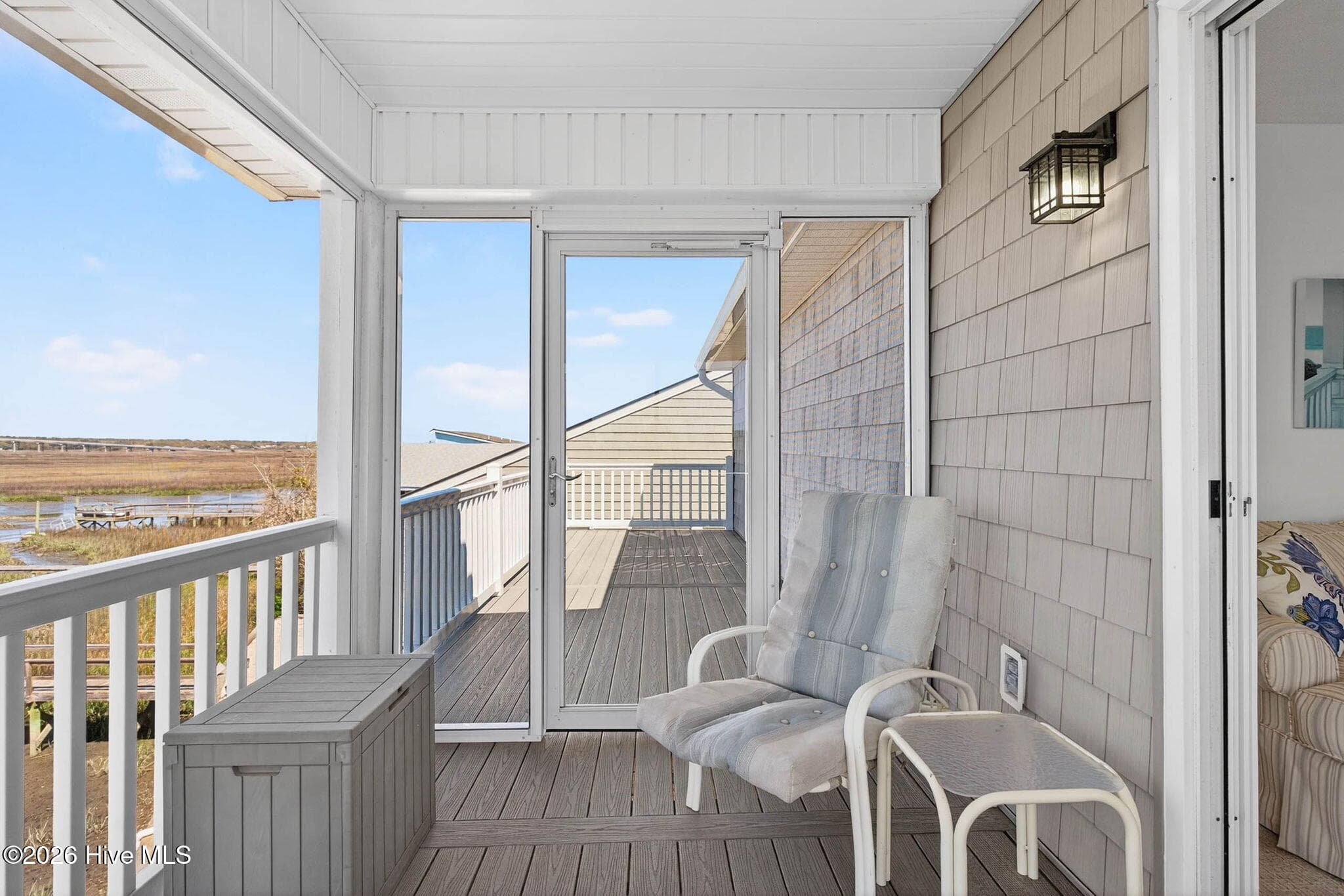 Covered porch entry with seating area and easy access to outdoor living spaces. - 1206 N Shore Drive W, Sunset Beach, NC 28468, Sunset Beach