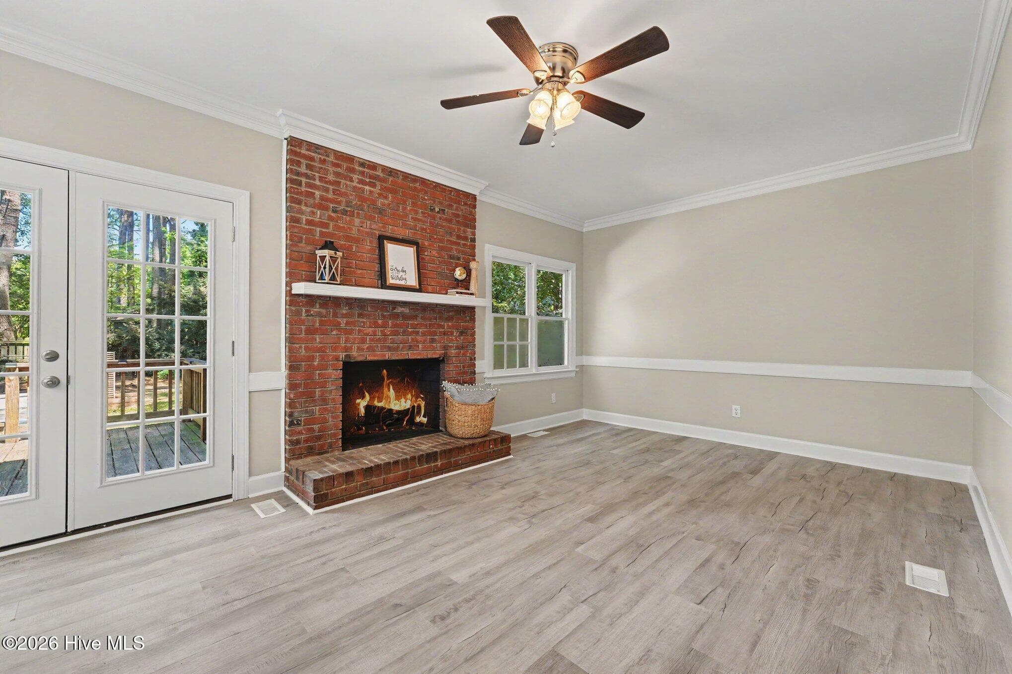 Living room with crown and chair moldings, ceiling fan and cozy gas fireplace. French doors exit to large deck and hot tub. - 2112 Burnside Drive NW, Wilson, NC 27896