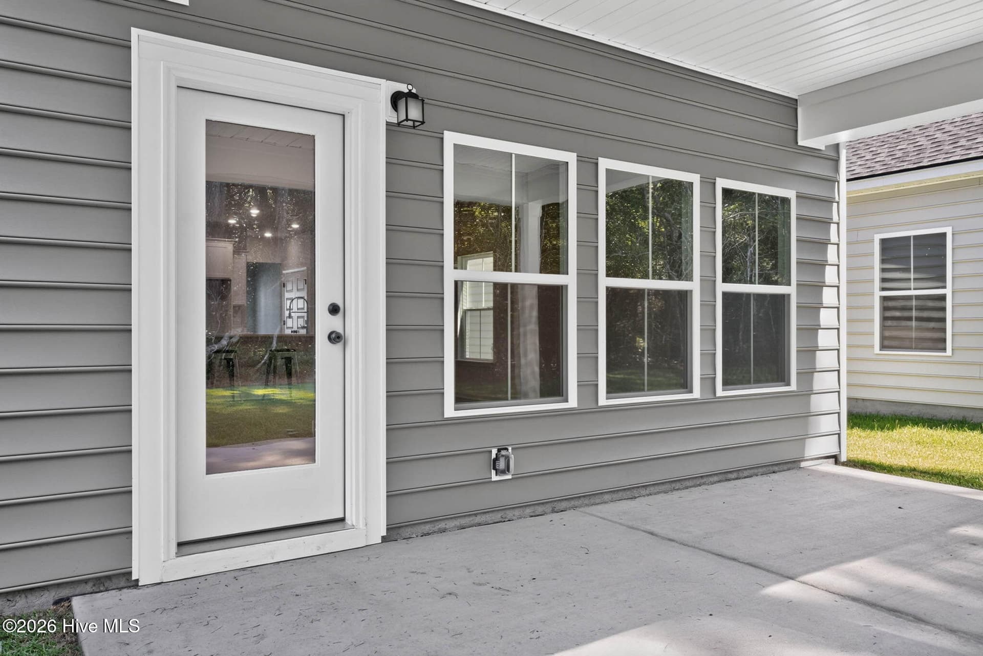 Covered rear patio providing a comfortable outdoor living area overlooking the backyard. - 3447 Sandhill Crane Drive SW, Ocean Isle Beach, NC 28469