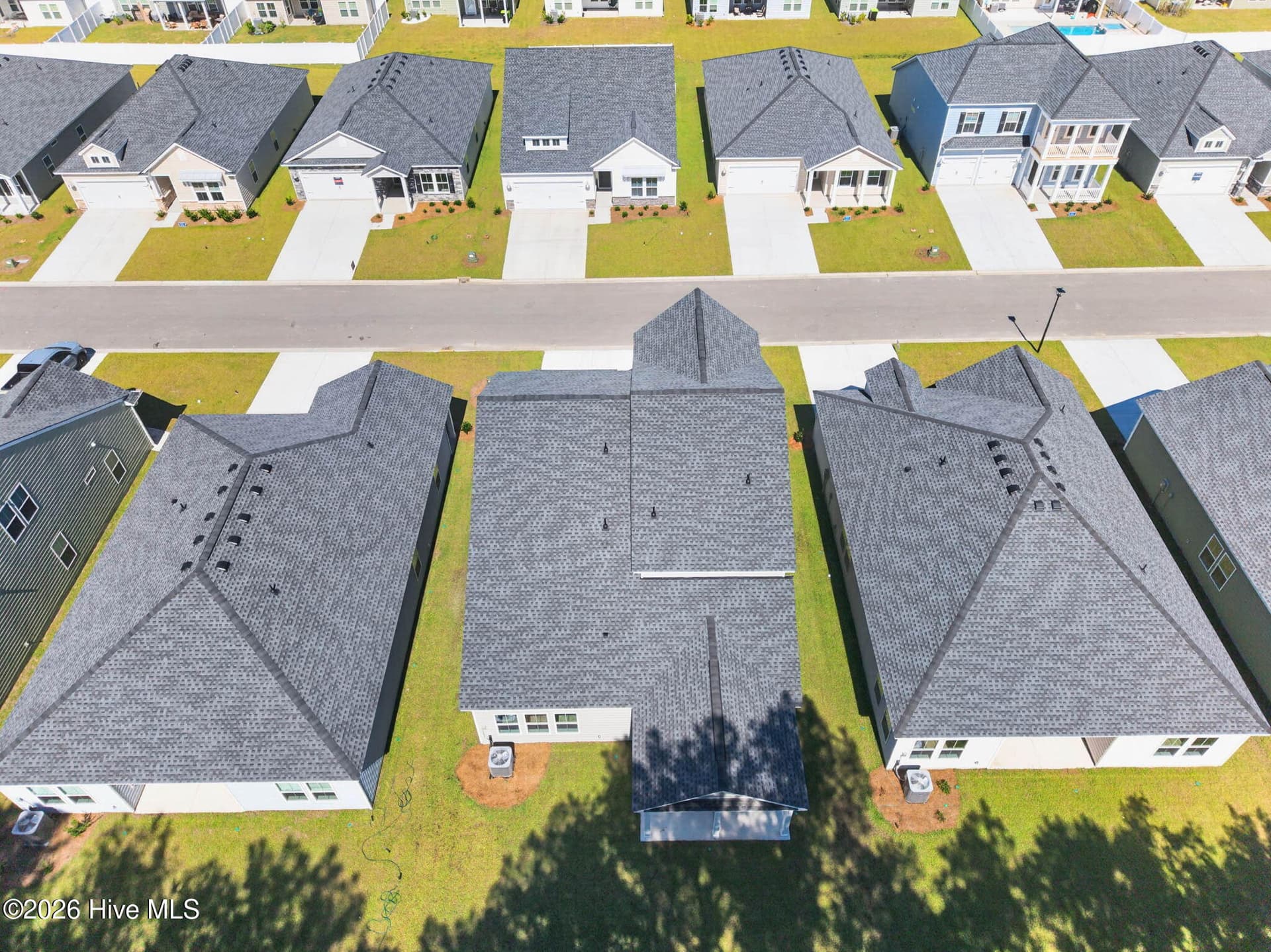 Aerial view highlighting the home's backyard, neighboring properties, and wooded common area behind the homesite. - 3447 Sandhill Crane Drive SW, Ocean Isle Beach, NC 28469
