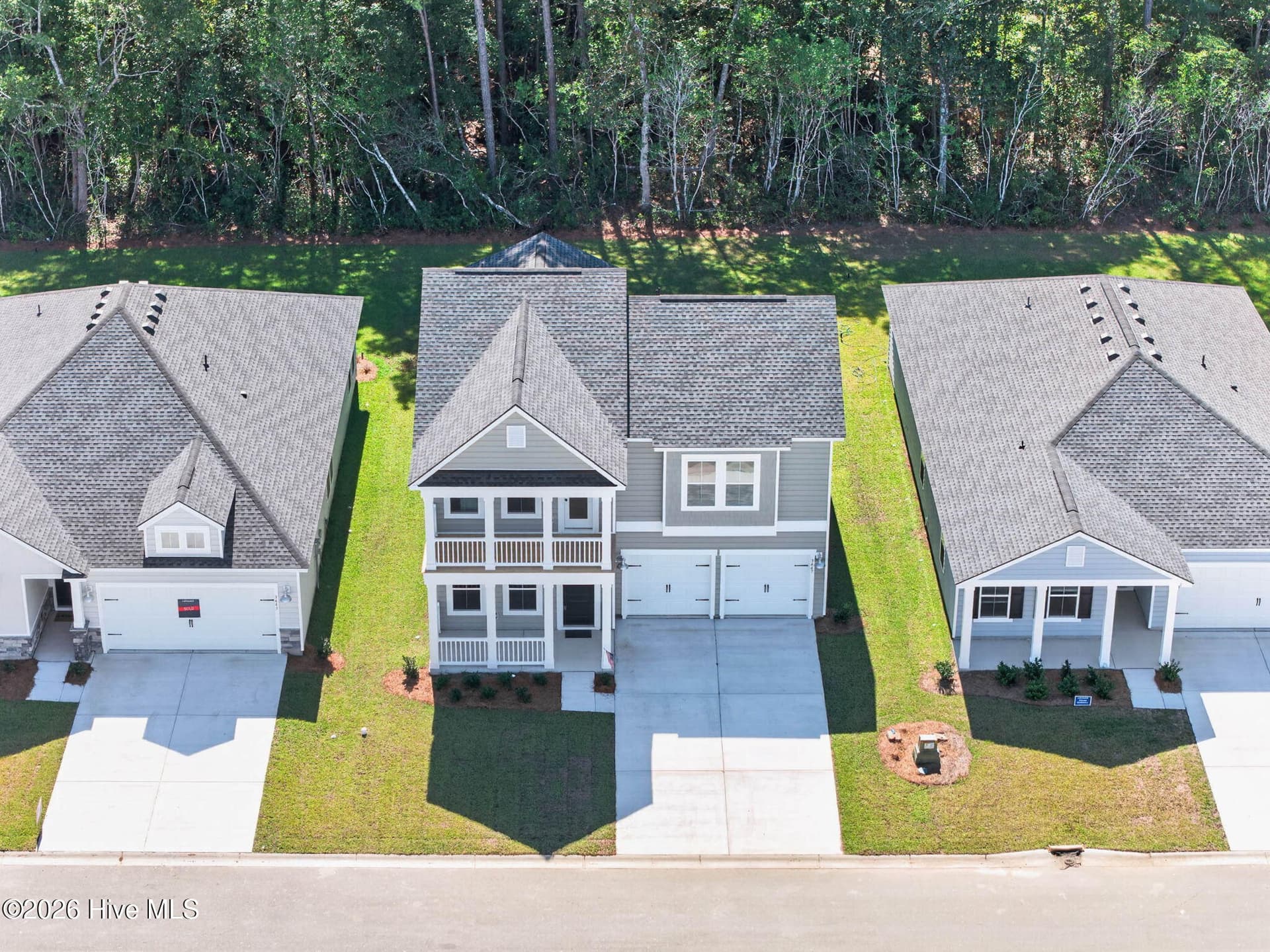 Front aerial view of this never-occupied Lennar Kensington featuring two-story coastal architecture and a spacious driveway. - 3447 Sandhill Crane Drive SW, Ocean Isle Beach, NC 28469