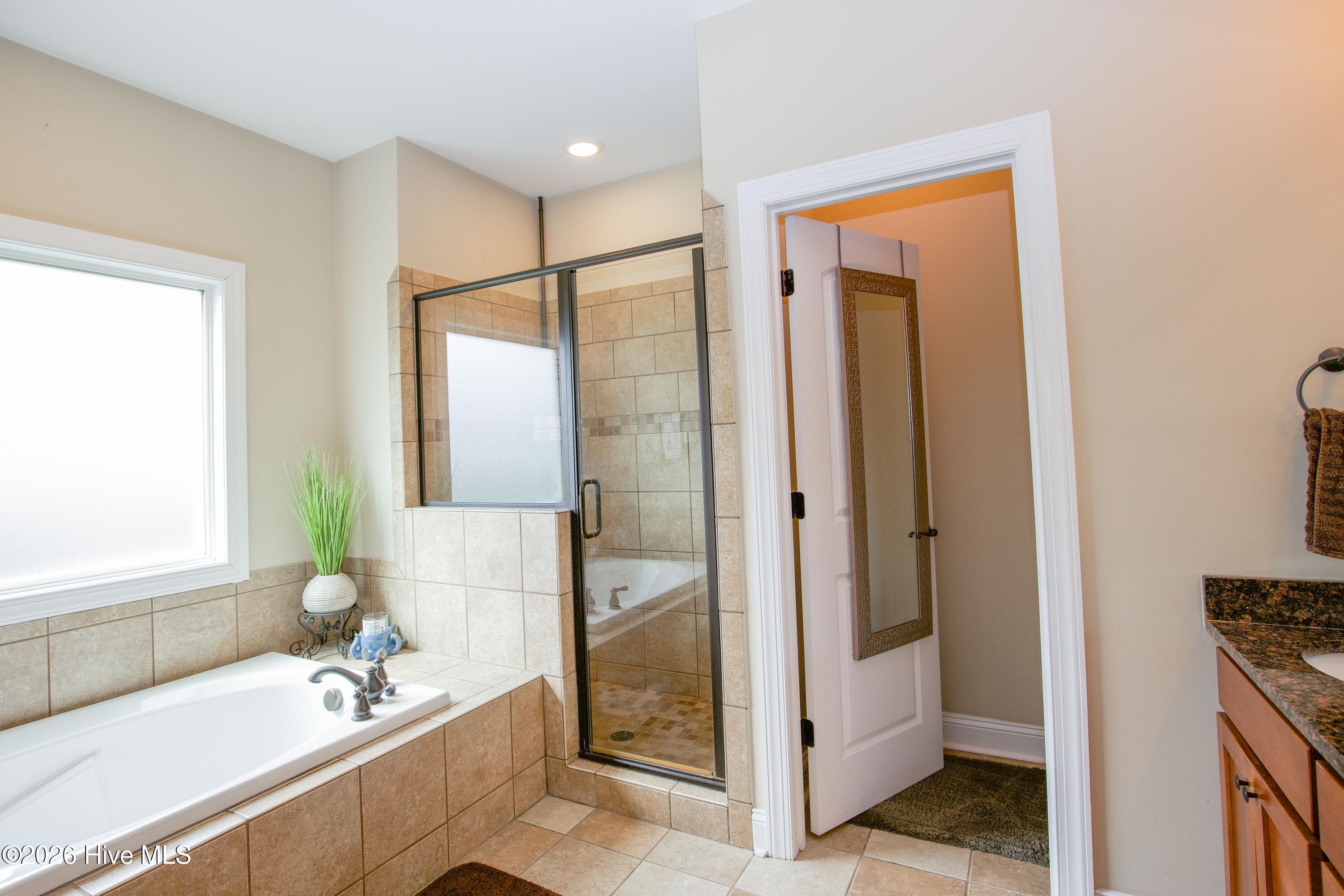 Primary bath seen from the vanity, with the soaking tub and tiled shower. - 899 Seagull Drive, Vass, NC 28394, Vass