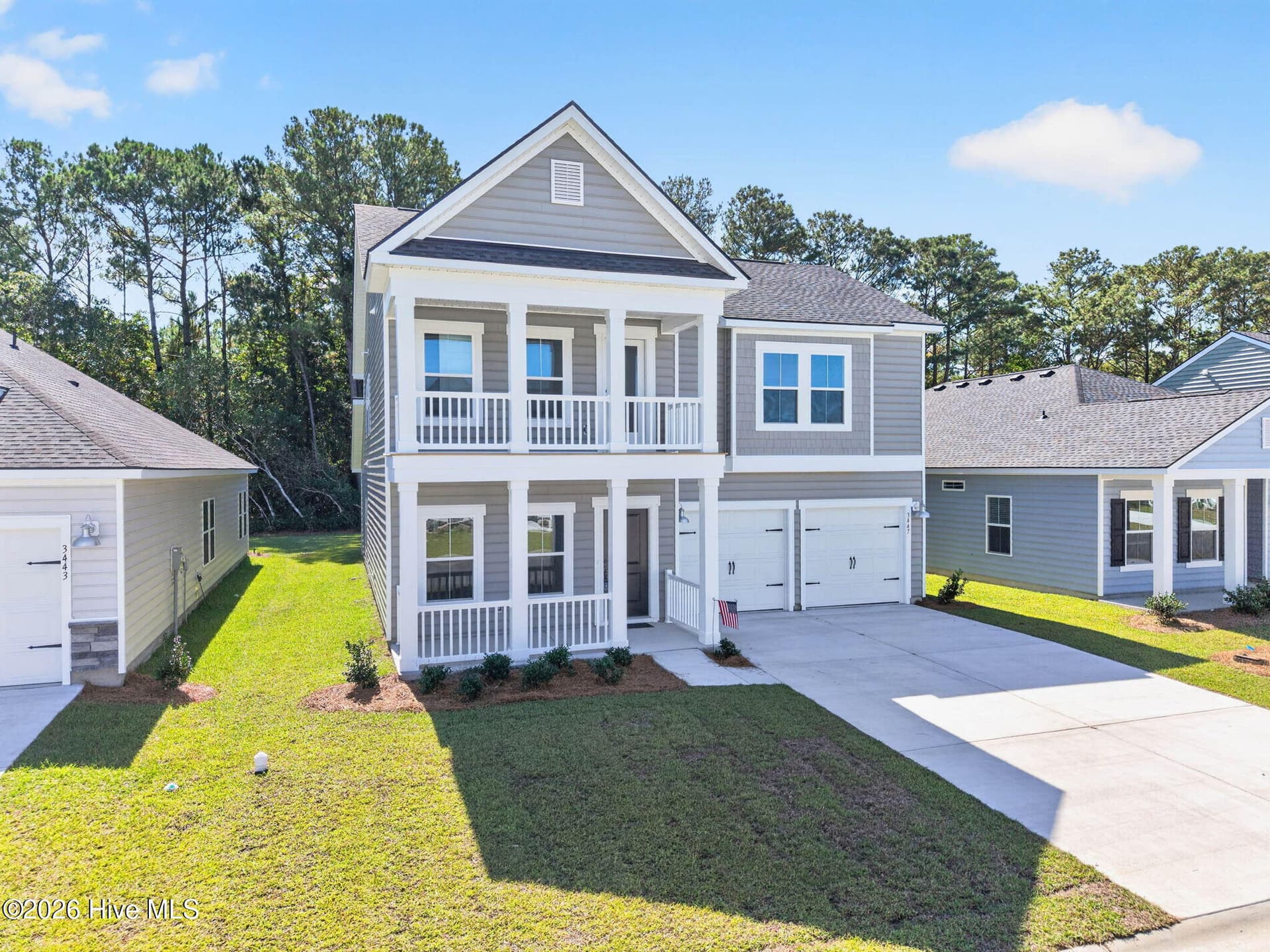 Beautiful two-story coastal home with covered front porch, second-floor balcony, and attached two-car garage. - 3447 Sandhill Crane Drive SW, Ocean Isle Beach, NC 28469