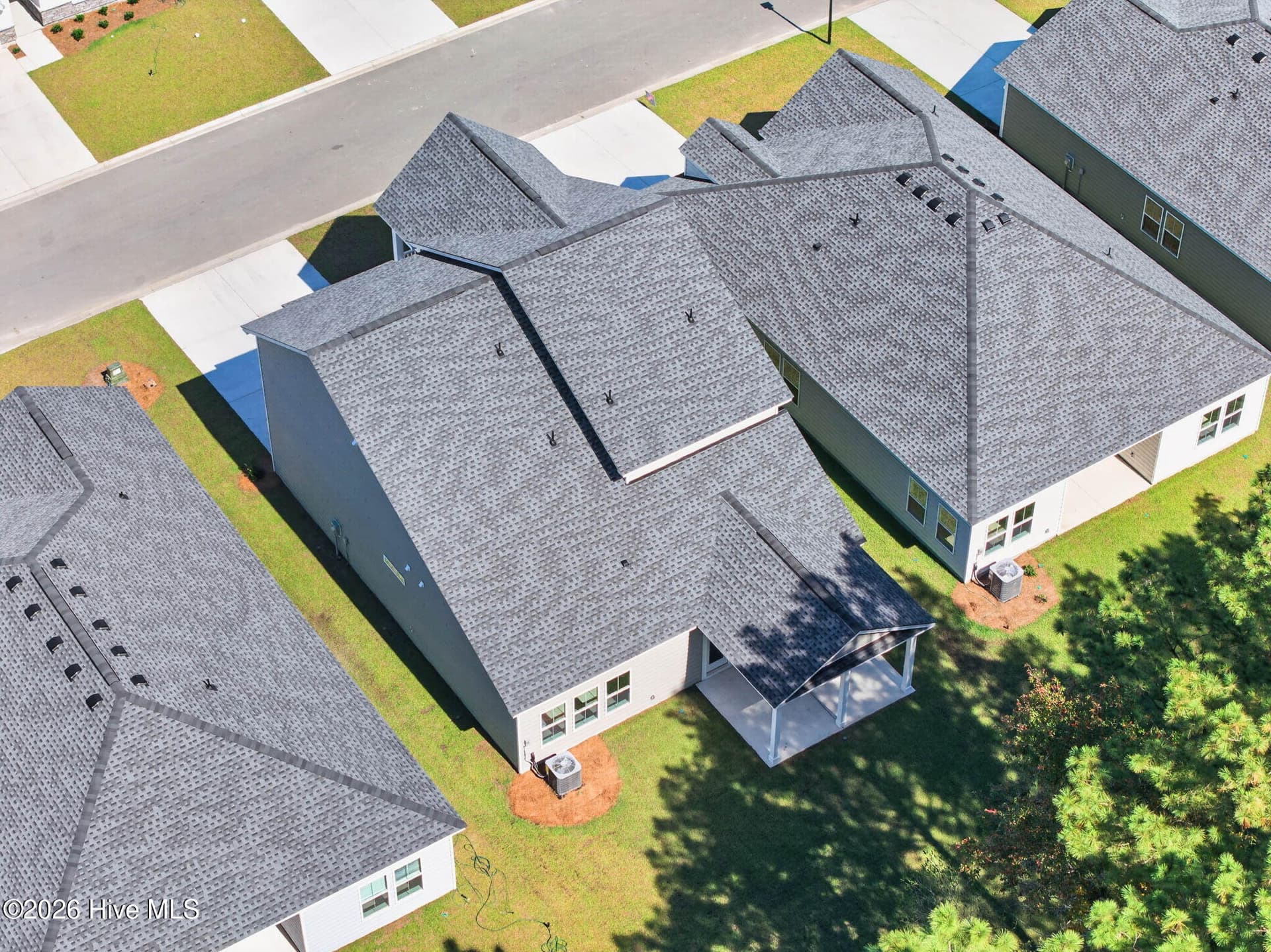 Elevated aerial view showcasing the home's roofline, covered outdoor living areas, and surrounding neighborhood. - 3447 Sandhill Crane Drive SW, Ocean Isle Beach, NC 28469
