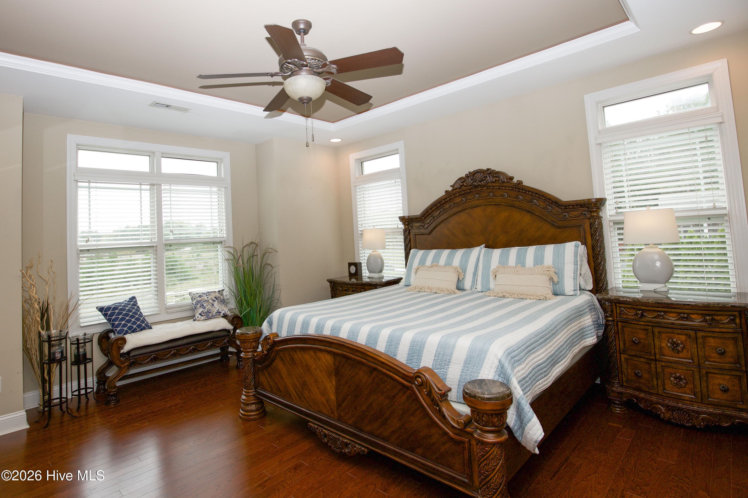 Main-level primary bedroom with a tray ceiling and ceiling fan. - 899 Seagull Drive, Vass, NC 28394, Vass