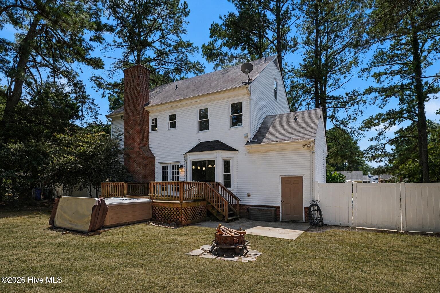 Rear view of home shows exterior storage, patio with firepit, large deck and hot tub. - 2112 Burnside Drive NW, Wilson, NC 27896