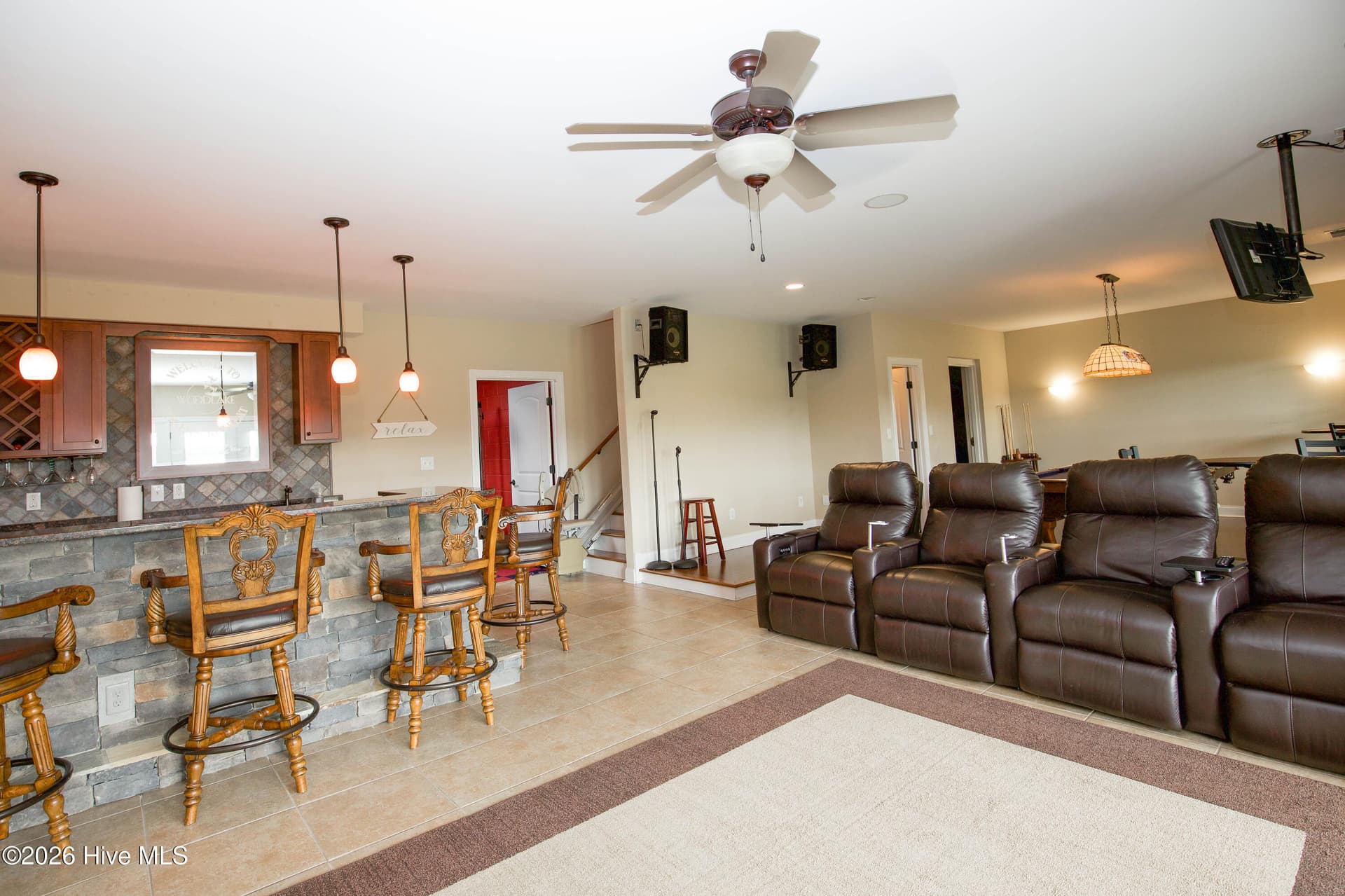 Finished walkout lower level featuring a media area, stone-front wet bar, and stairlift providing assisted access between levels. - 899 Seagull Drive, Vass, NC 28394