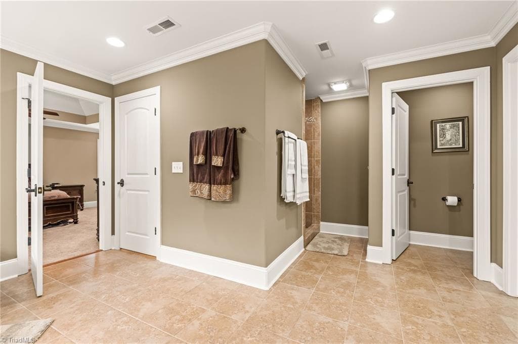 View in primary bathroom from the vanities - closed door on the left leads to walk up attic. Open door to the right leads to the toilet area. Space in the middle leads to tile shower - 6202 Herons Nest Court, Oak Ridge NC 27310, Oak Ridge