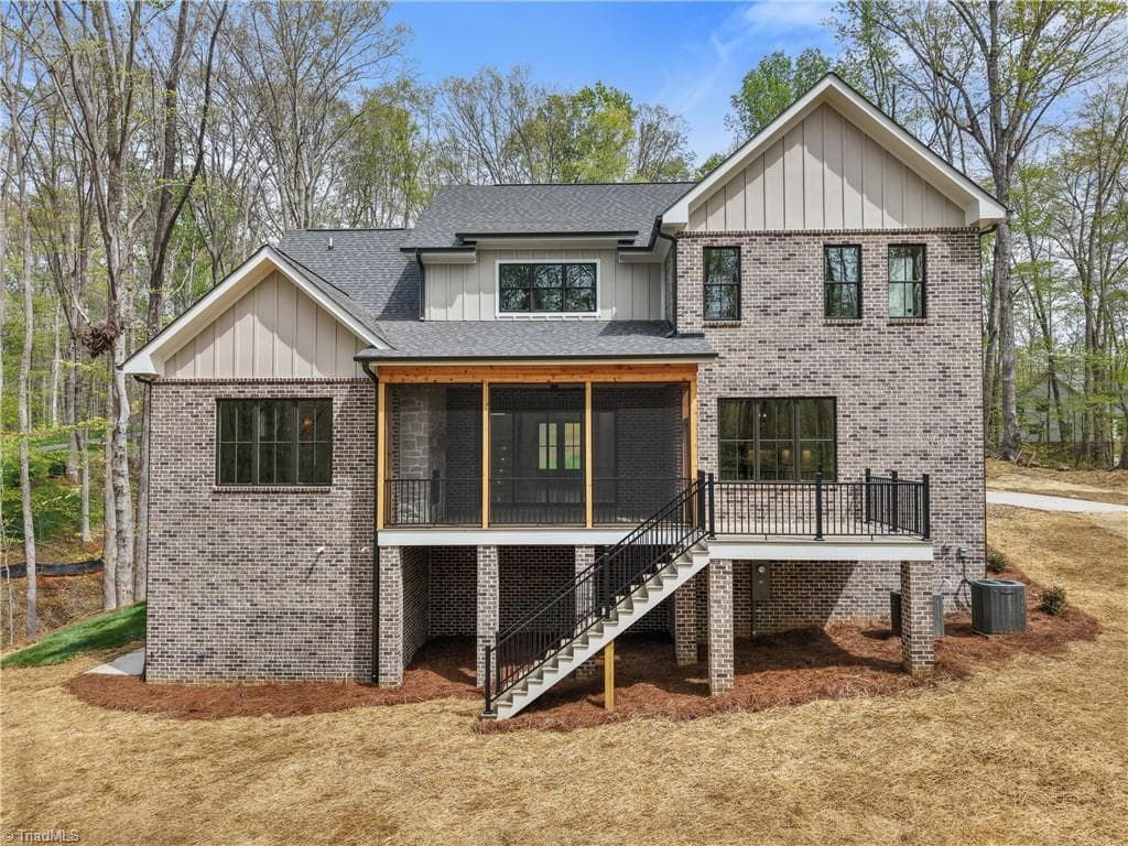 Rear elevation showcases the covered porch, screened outdoor living area, and walkout basement below. - 9664 Lissara Camp Court, Lewisville NC 27023, Lewisville