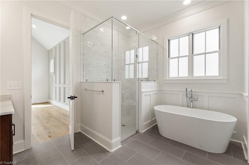 Spa-like primary bath with freestanding tub, oversized shower, and refined finishes. - 9664 Lissara Camp Court, Lewisville NC 27023, Lewisville