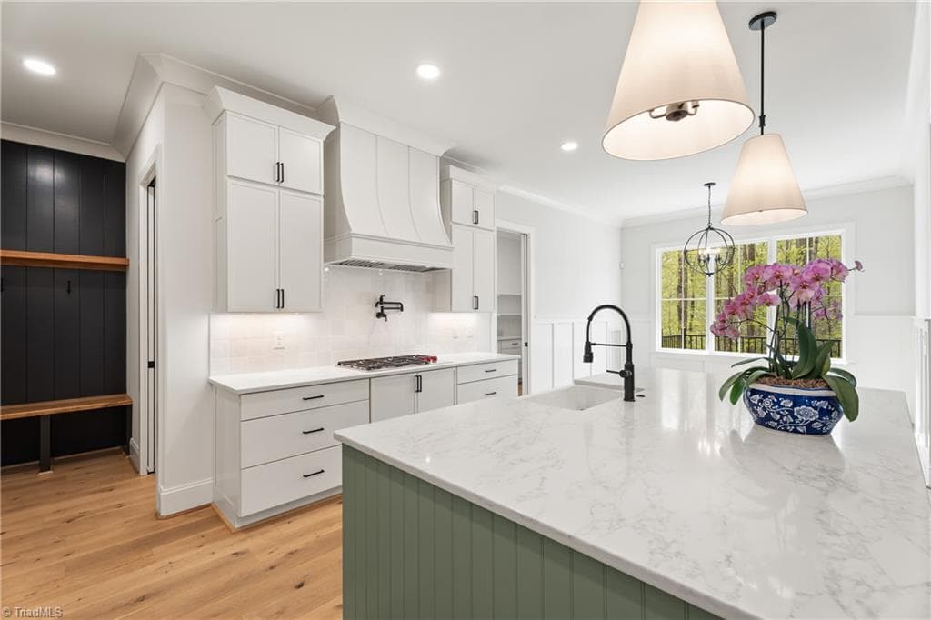 Kitchen details include custom cabinetry, a statement vent hood, and designer lighting. - 9664 Lissara Camp Court, Lewisville NC 27023, Lewisville