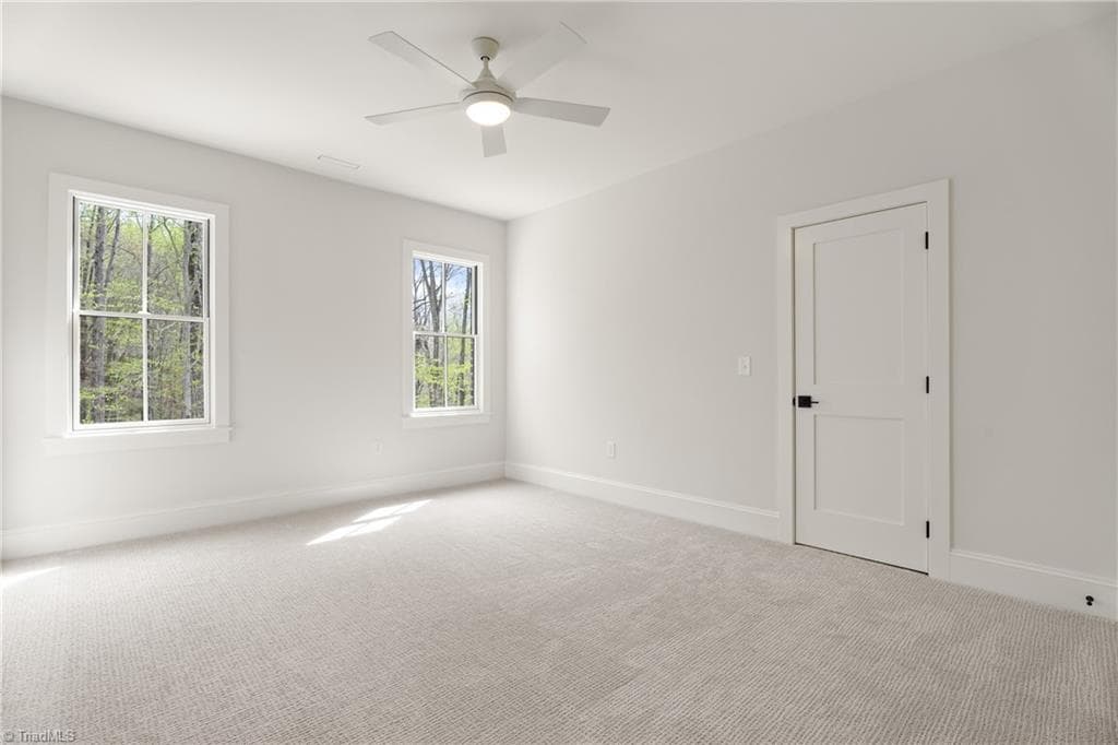 Spacious secondary bedroom with wooded views, soft carpet, and great natural light. - 9664 Lissara Camp Court, Lewisville NC 27023, Lewisville