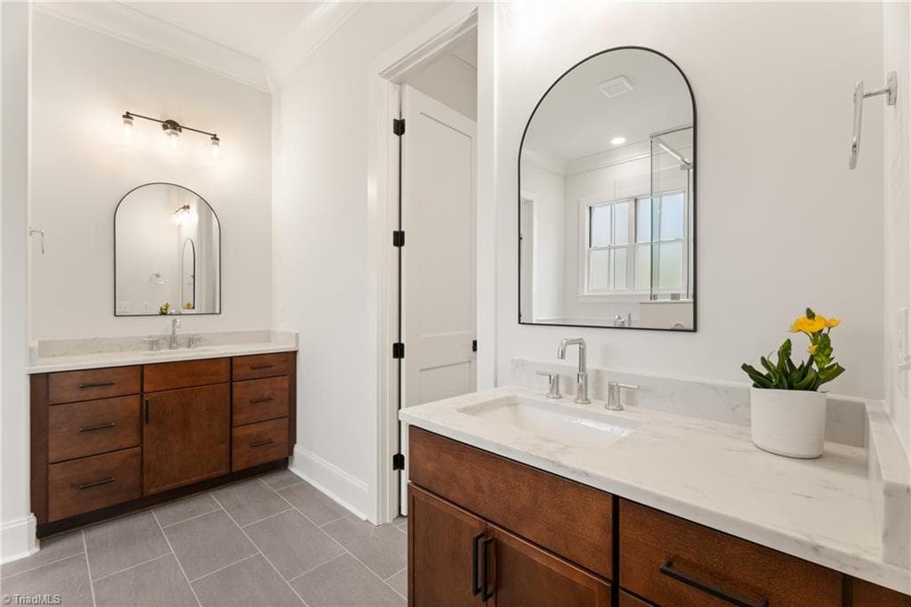 Dual vanities with warm wood cabinetry add contrast and character to the primary bath. - 9664 Lissara Camp Court, Lewisville NC 27023, Lewisville