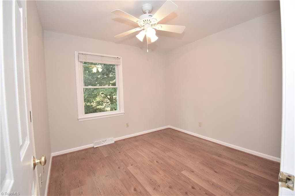 The first guest bedroom features a ceiling fan and laminate floors. - 8546 Hudson-James Road, Summerfield NC 27358, Summerfield