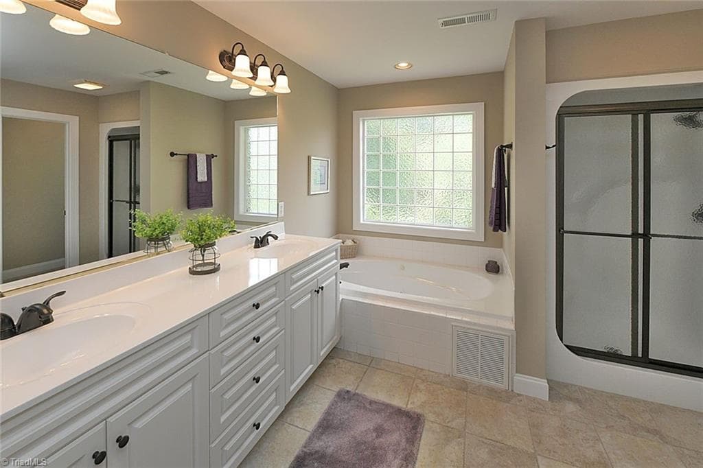 Ready for relaxation? Primary Bath Features a jetted tub that was recently serviced and a newly installed glass shower door for the walk-in shower. - 1101 Clyde Edgerton Drive, Kernersville NC 27284, Kernersville