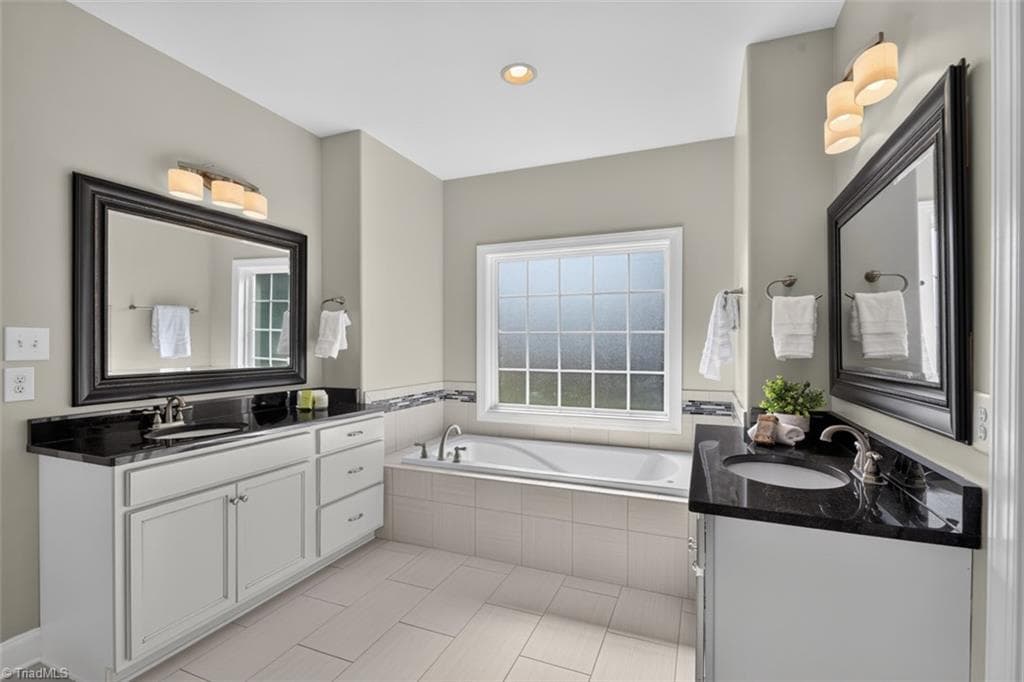 Primary bath with jetted tub, double vanities, oversized shower, and spacious closet. - 7807 Winterbourne Drive, Summerfield NC 27358, Summerfield