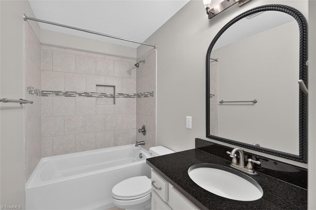 Ensuite bathroom w/second bedroom features tile, granite counters, and storage cabinet. - 7807 Winterbourne Drive, Summerfield NC 27358, Summerfield