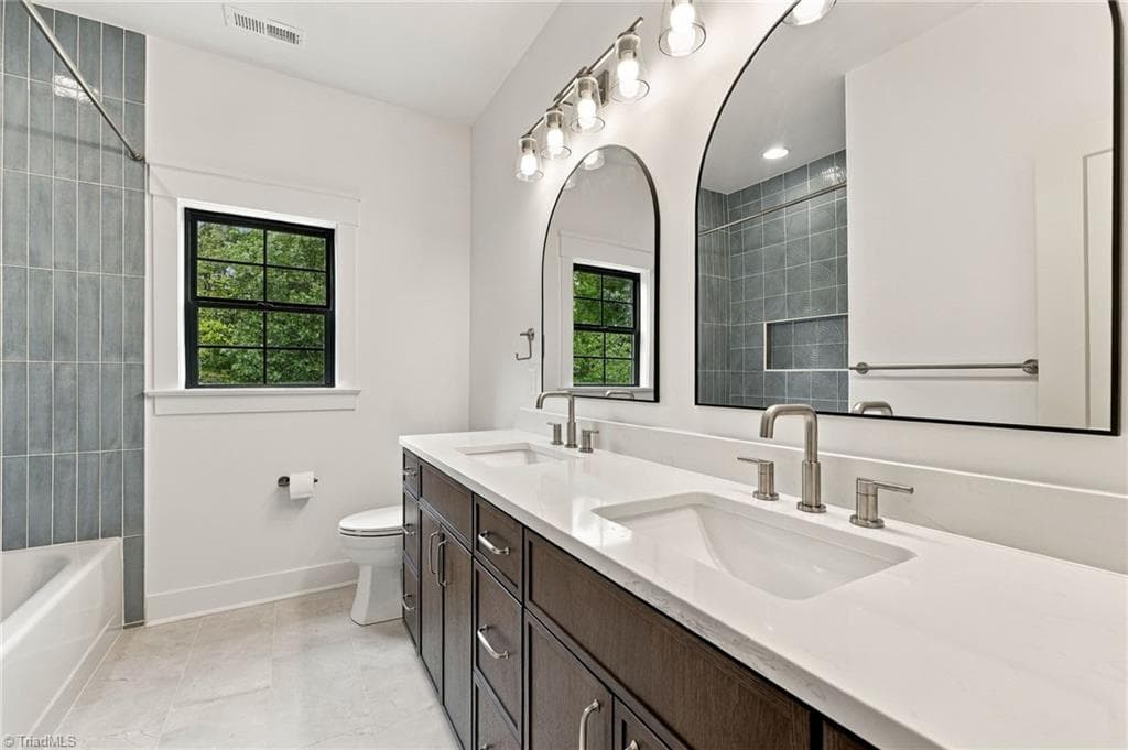 A true designer statement, the guest bath showcases exquisite custom tilework highlighted by an artistic circular motif, creating a sophisticated and distinctive space with exceptional attention to detail. - 224 Pearson Farm Road, Summerfield NC 27358, Summerfield