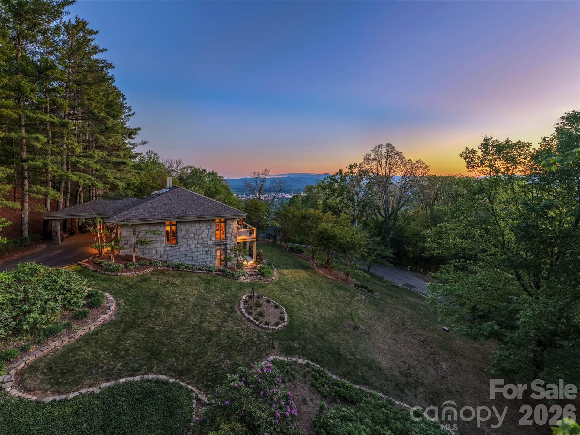 Arriving through winding gardens and a graceful entrance, the glow of the city lights creates an unforgettable welcome each evening. - 65 Crestwood Road, Asheville
