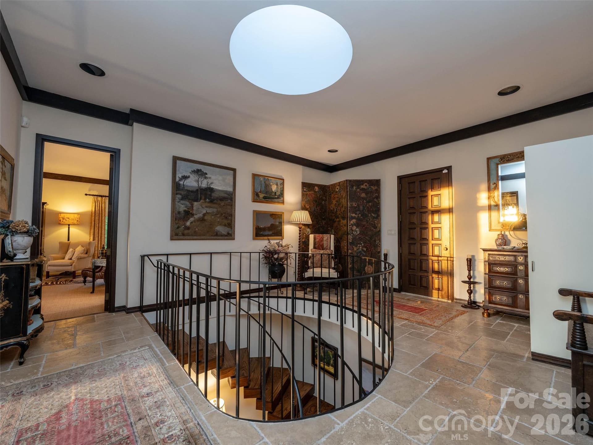 A 1970s front door embracing a piece of architectural history opens to early morning or late afternoon light from the original skylight that highlights circular staircase - 65 Crestwood Road, Asheville