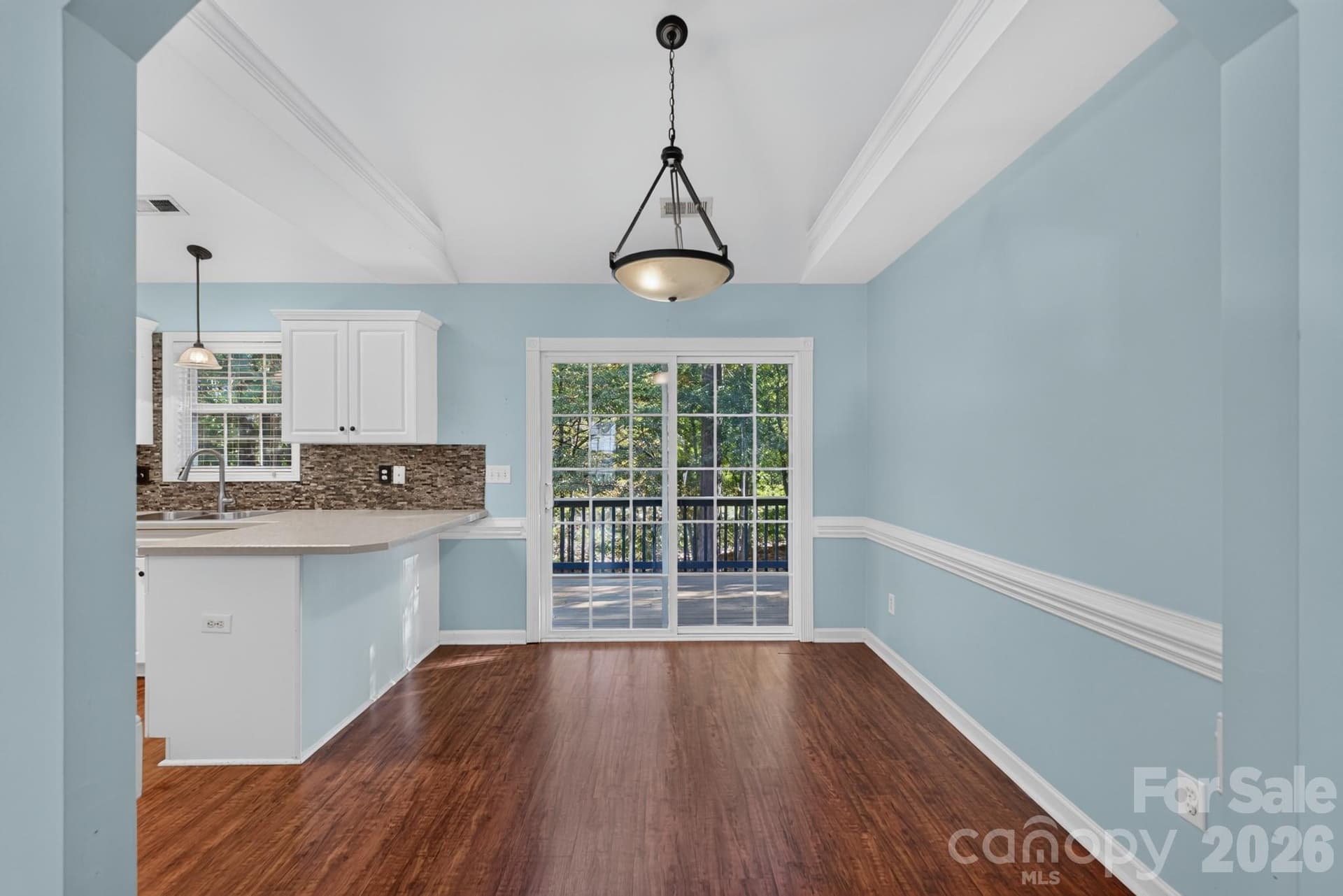 Formal dining area adorned with stylish chair-rail molding, designer lighting fixture, and sliding door access. - 702 Painted Lady Court, Rock Hill