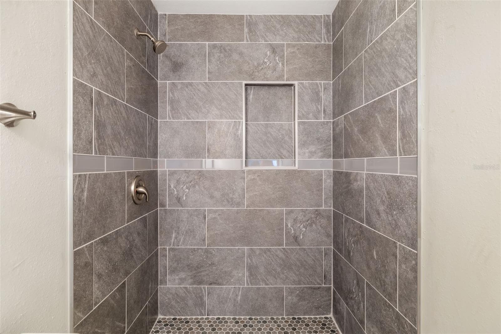 Walk-In ShowerWalk-in shower with custom tile work and built-in niche for convenience. - 2513 AVENUE B #B, BRADENTON BEACH