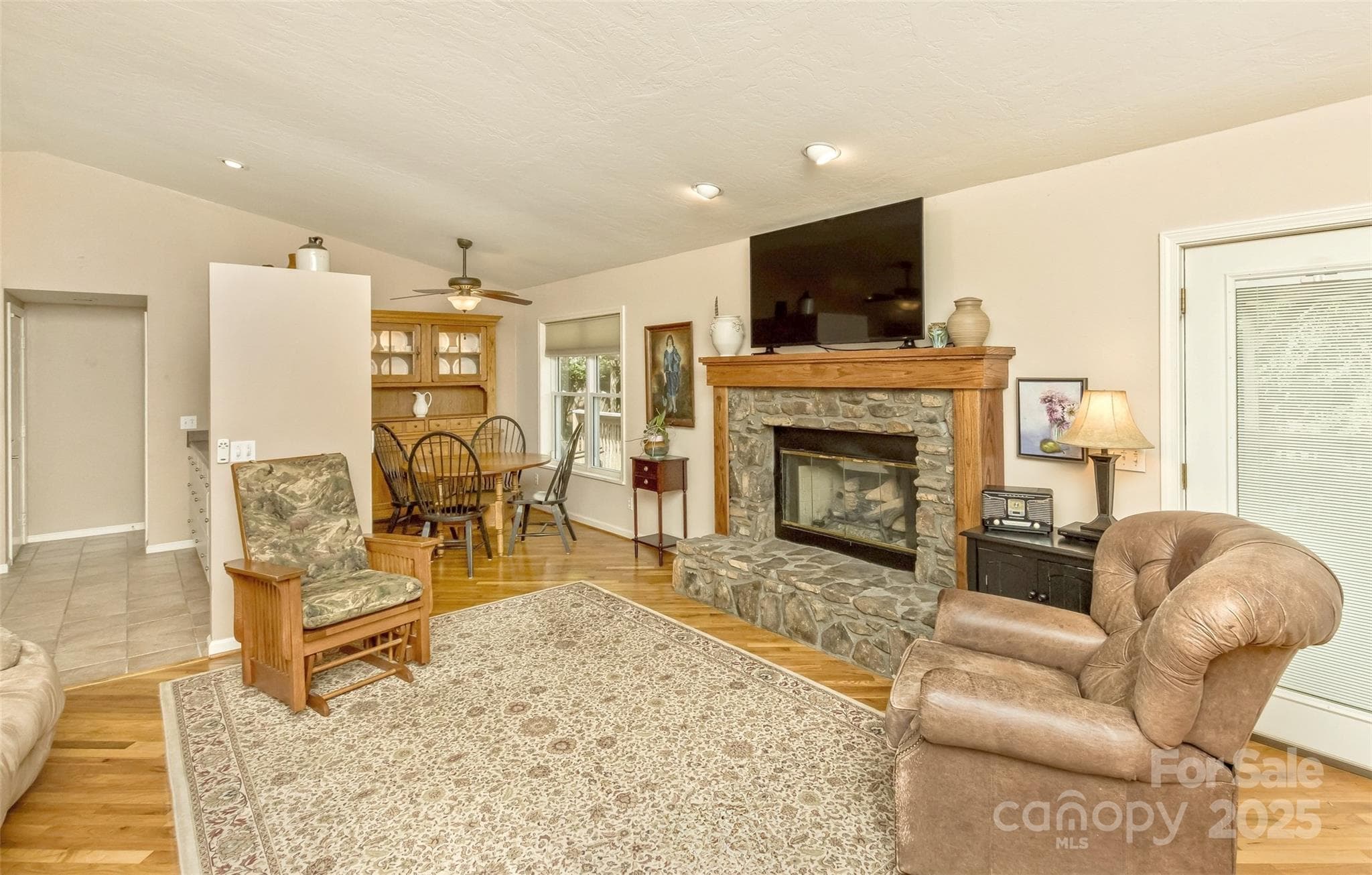 The great room is cozy with a beautiful stone fireplace, oak mantel and natural gas logs. The mantel is designed with chases in the columns to hide wiring needs. - Asheville