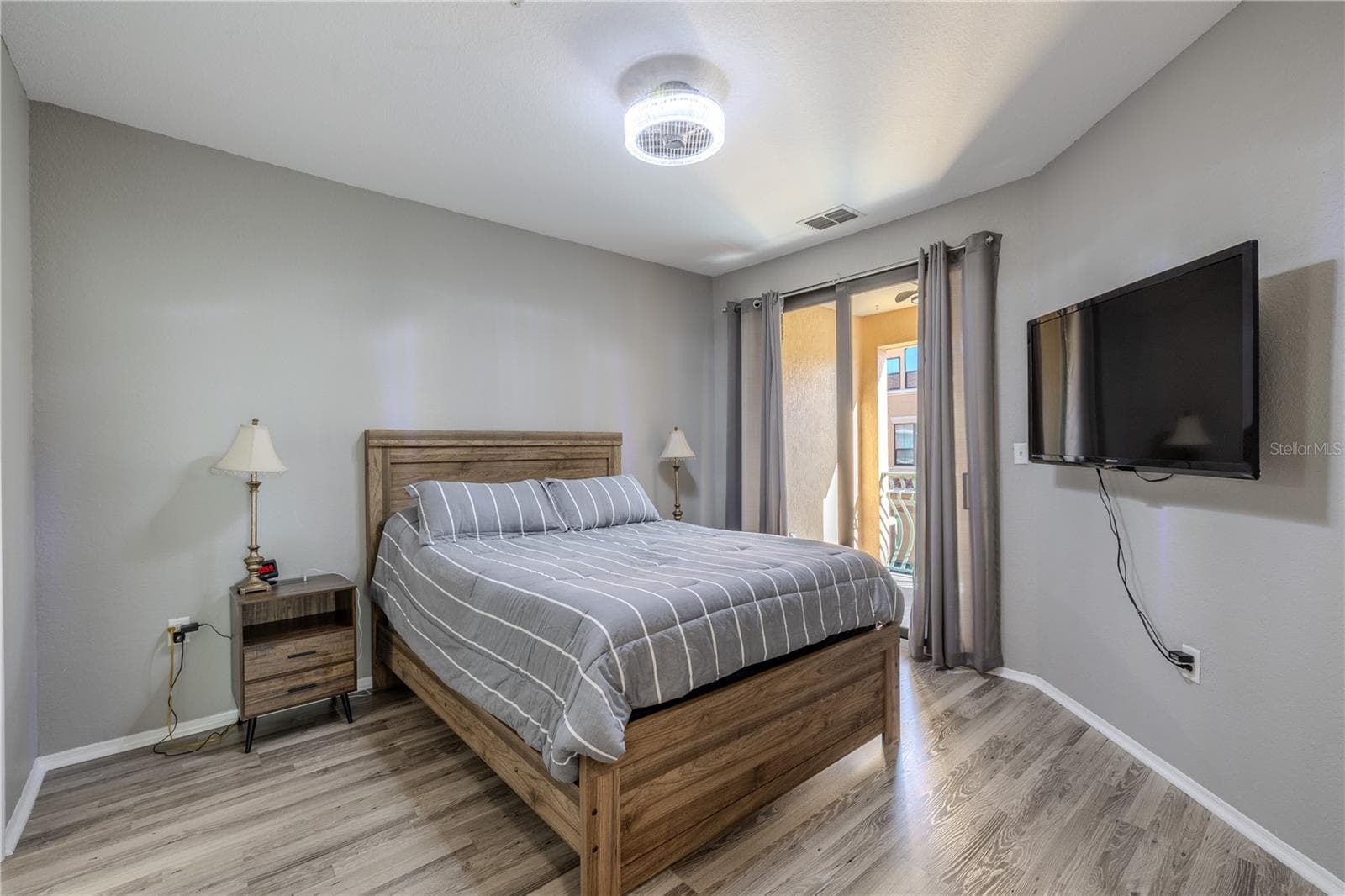 Primary bedroom retreat featuring sliding glass doors to the private balcony, soft neutral tones, modern lighting, and easy access to the main living area, creating a bright and comfortable space to unwind. - 2738 VIA TIVOLI #220B, CLEARWATER