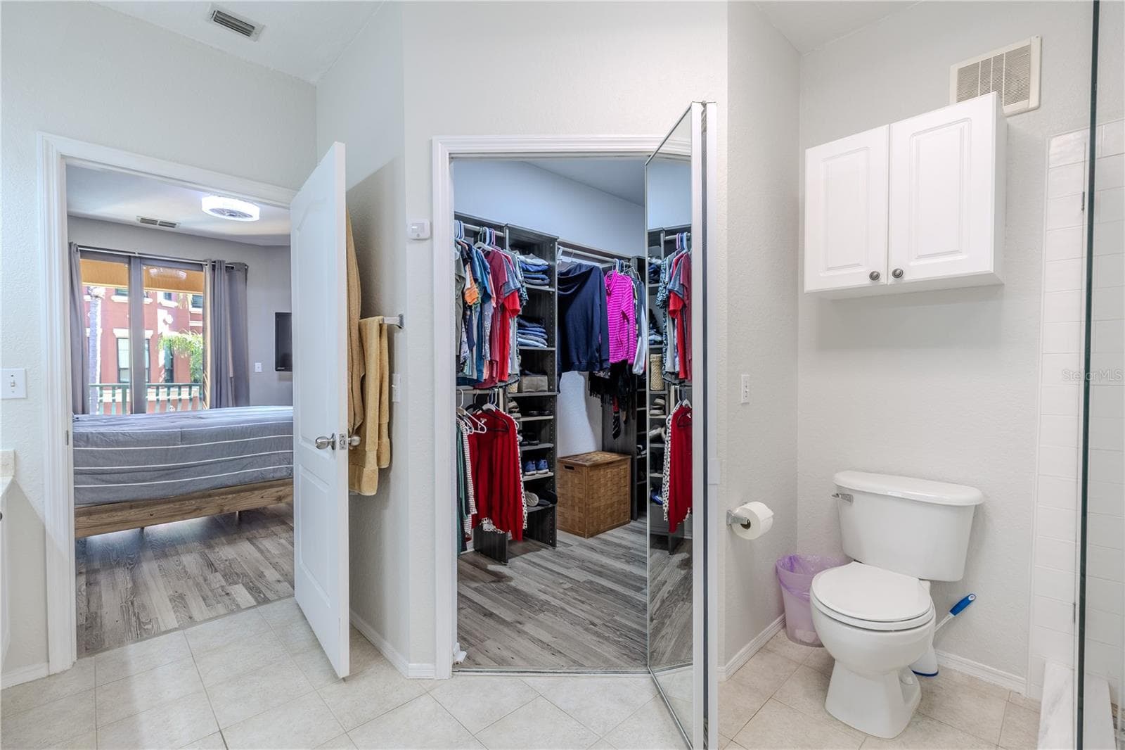 Primary bath area with a walk-in closet, private water closet, and a glass-enclosed shower, with easy access back to the bedroom and balcony beyond. - 2738 VIA TIVOLI #220B, CLEARWATER