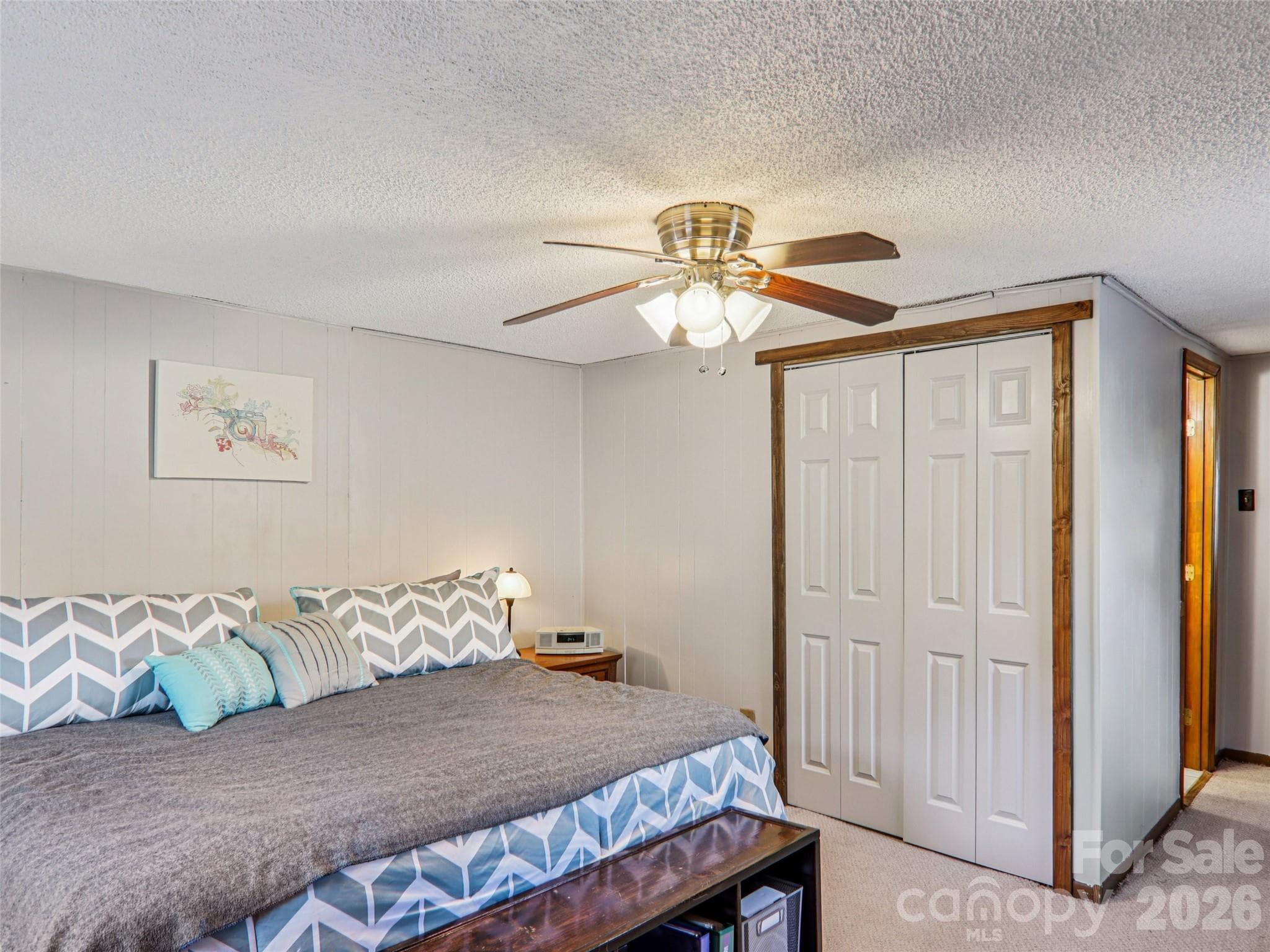 Primary bedroom with carpeted flooring, ceiling fan, closet, and ensuite bathroom entrance in the background - 7 Landon Mountain Lane, Weaverville