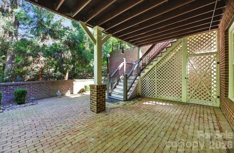 Brick paver patio below raised screened in deck. - Charlotte