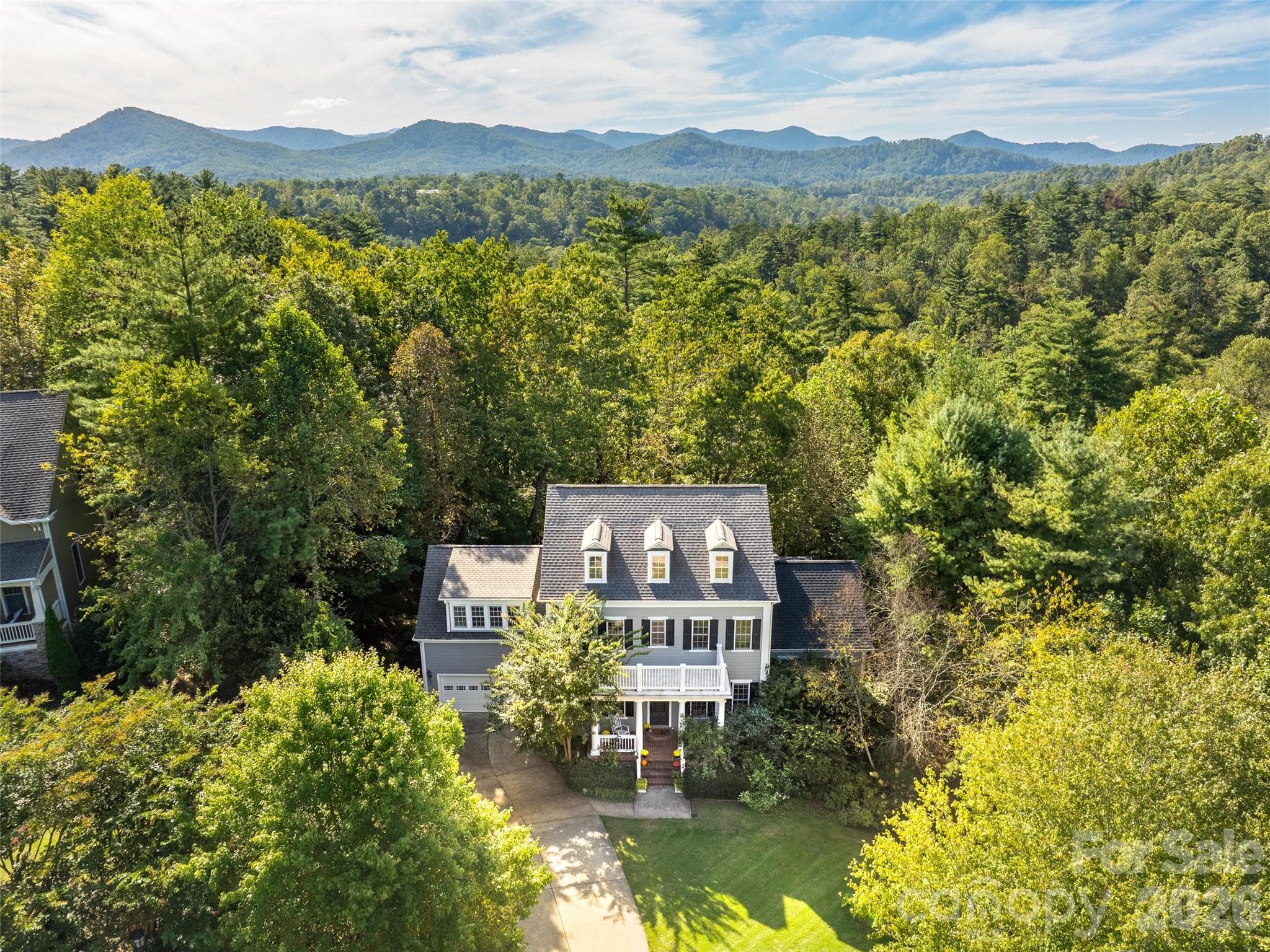 This impressive aerial view highlights the property's private, wooded setting with mountains rising in the distance - Asheville