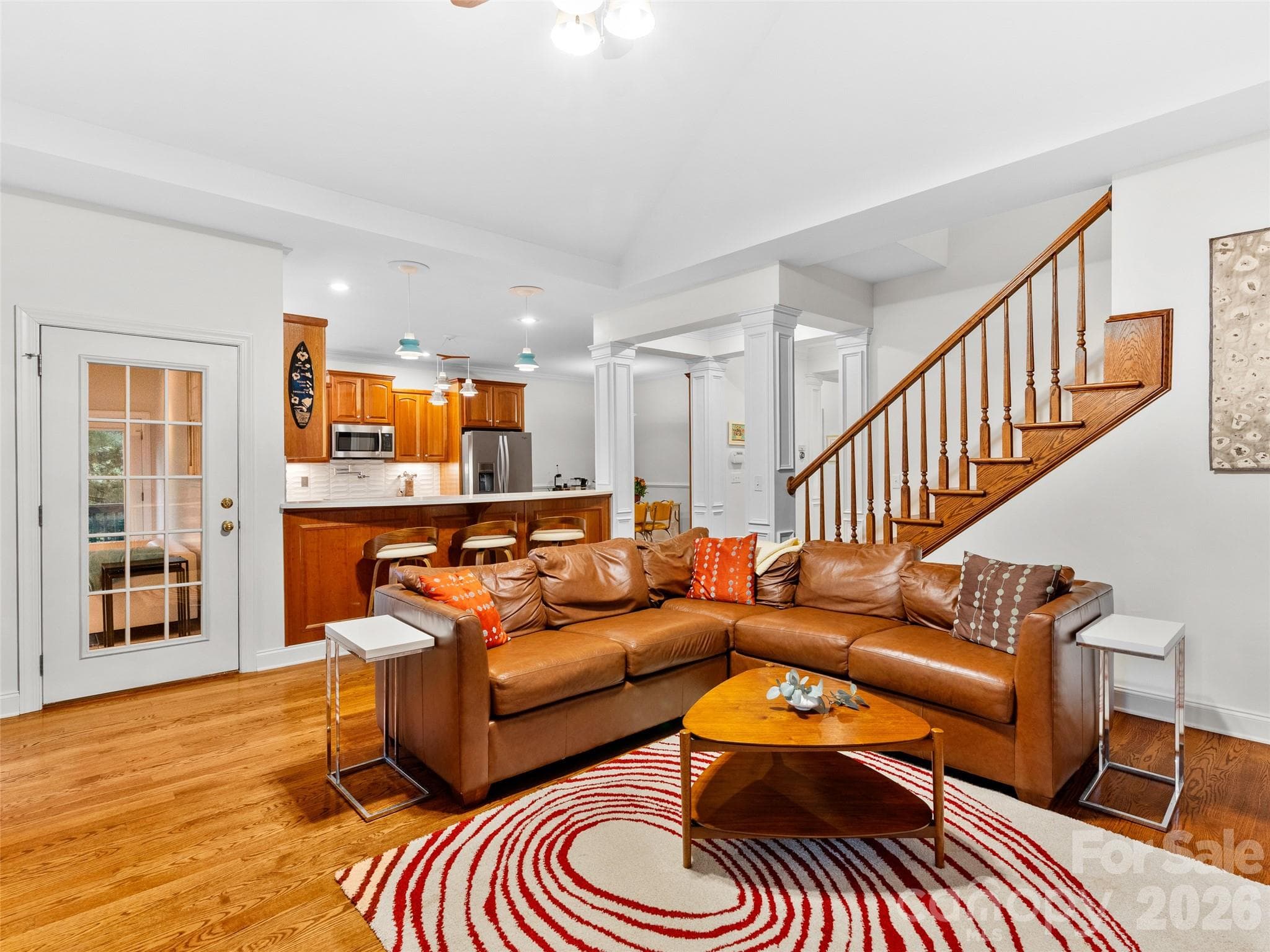 Bright and open, the family room offers hardwood floors, sightlines to the kitchen and its convenient countertop seating, and a wooden rail staircase that adds both character and connection to the upper level. - Asheville