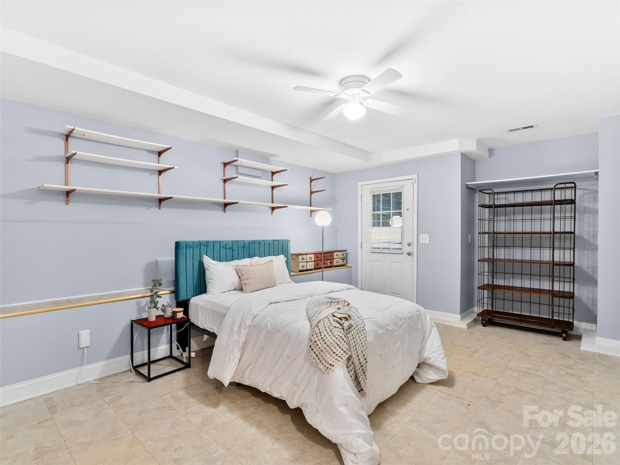This lower-level bedroom features tile floors and direct exterior access, offering a private entrance and flexible space for guests, an office, or a separate living area. - Asheville