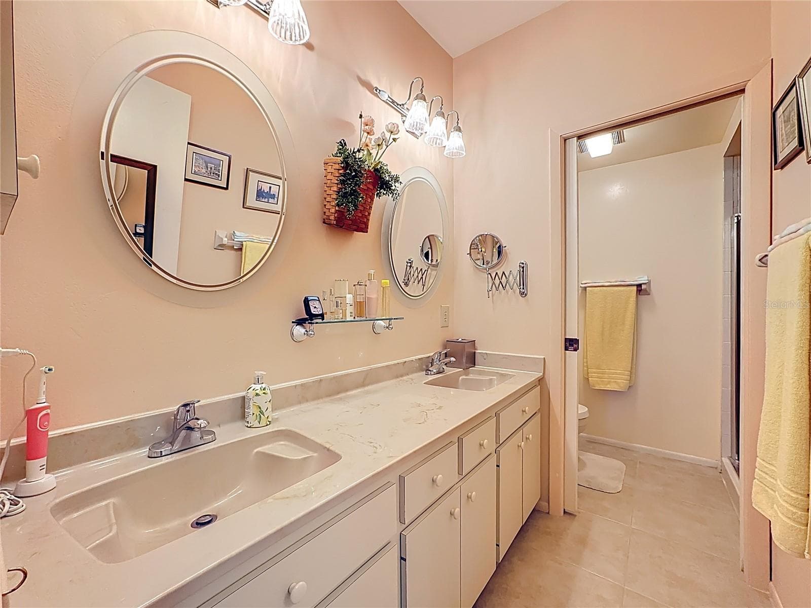 Primary ensuite bathroom with double sinks and pocket door with the toilet and shower. - 5611 GARDEN LAKES DR, BRADENTON