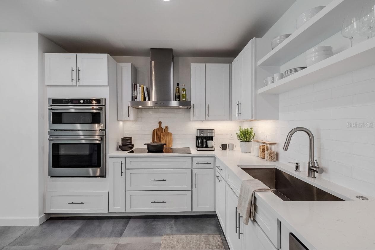 High-end stainless-steel appliances include a French door refrigerator, dishwasher, double wall ovens, and a vent hood. Large tile floors and under-cabinet lighting complete this bright, sophisticated culinary space. - 920 N OSCEOLA AVE #703, CLEARWATER