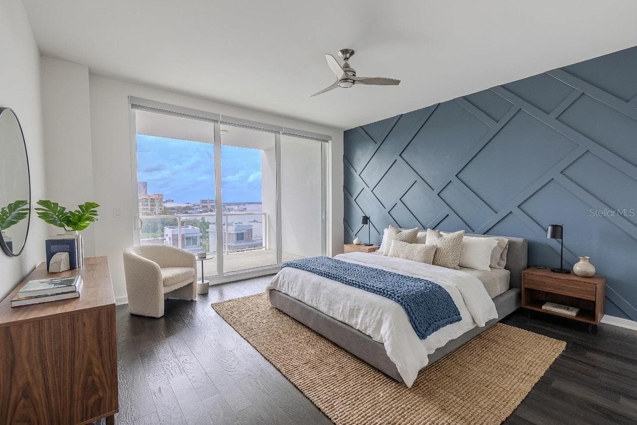 The primary bedroom features a striking custom accent wall that adds architectural depth and modern sophistication. Painted in a rich slate blue, the wall showcases a geometric grid pattern of raised molding, creating a dramatic focal point that complements the room’s sleek aesthetic. The textured design plays beautifully against the dark hardwood floors and natural light, offering the perfect balance of contemporary style and visual interest. - 920 N OSCEOLA AVE #703, CLEARWATER