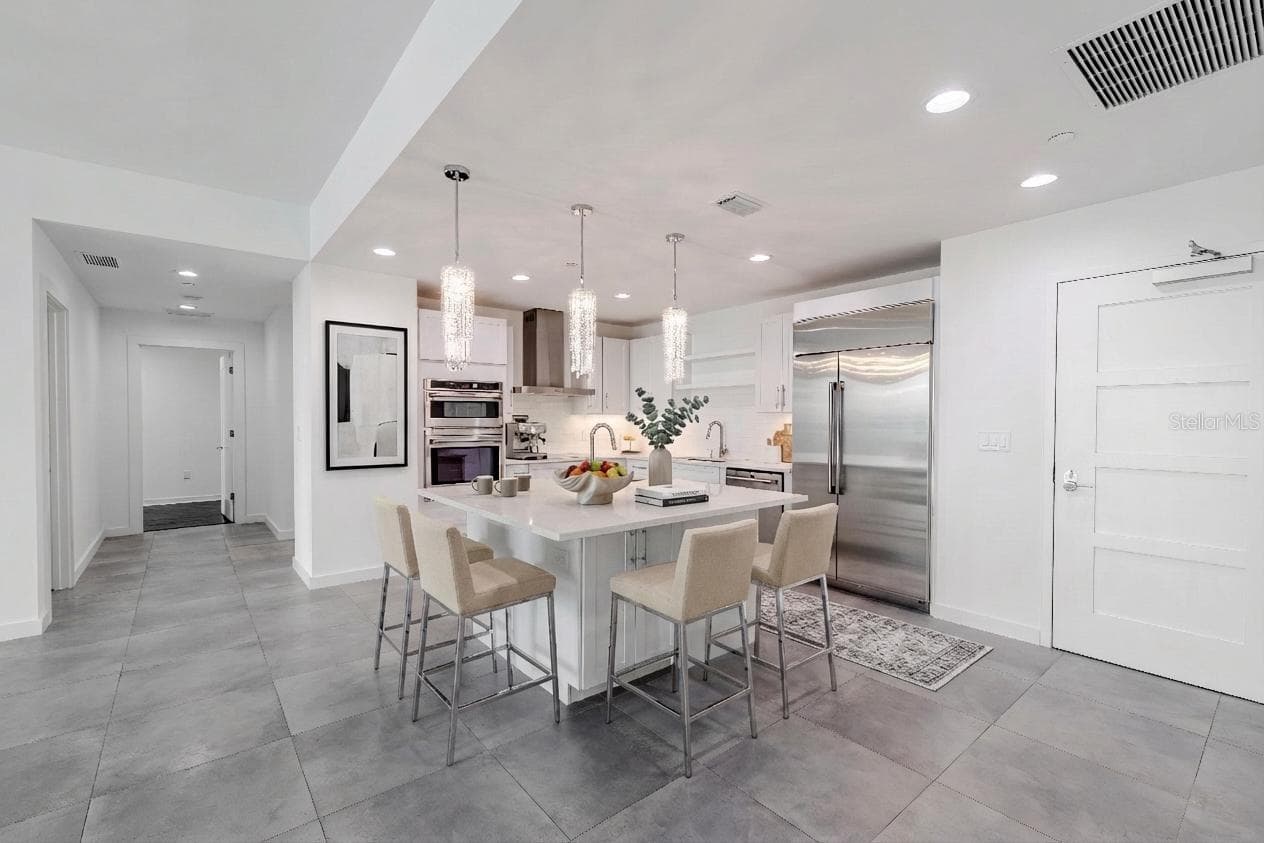 This show stopping modern kitchen is the centerpiece of the home, designed for both style and functionality. A sleek quartz island with storage and sink and bar seating anchors the open concept layout, framed by elegant crystal pendant lighting that adds a touch of glamour. - 920 N OSCEOLA AVE #703, CLEARWATER