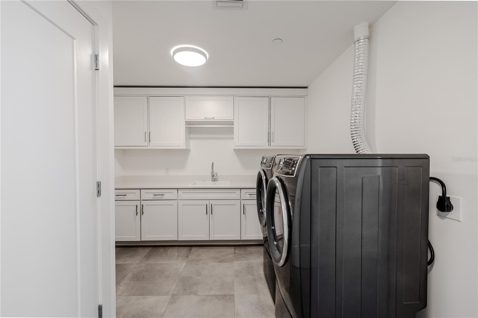 This spacious, well-appointed laundry room combines function and style with sleek cabinetry, quartz countertops, and abundant storage. A deep sink and full-size front-loading washer and dryer make laundry tasks effortless. - 920 N OSCEOLA AVE #703, CLEARWATER