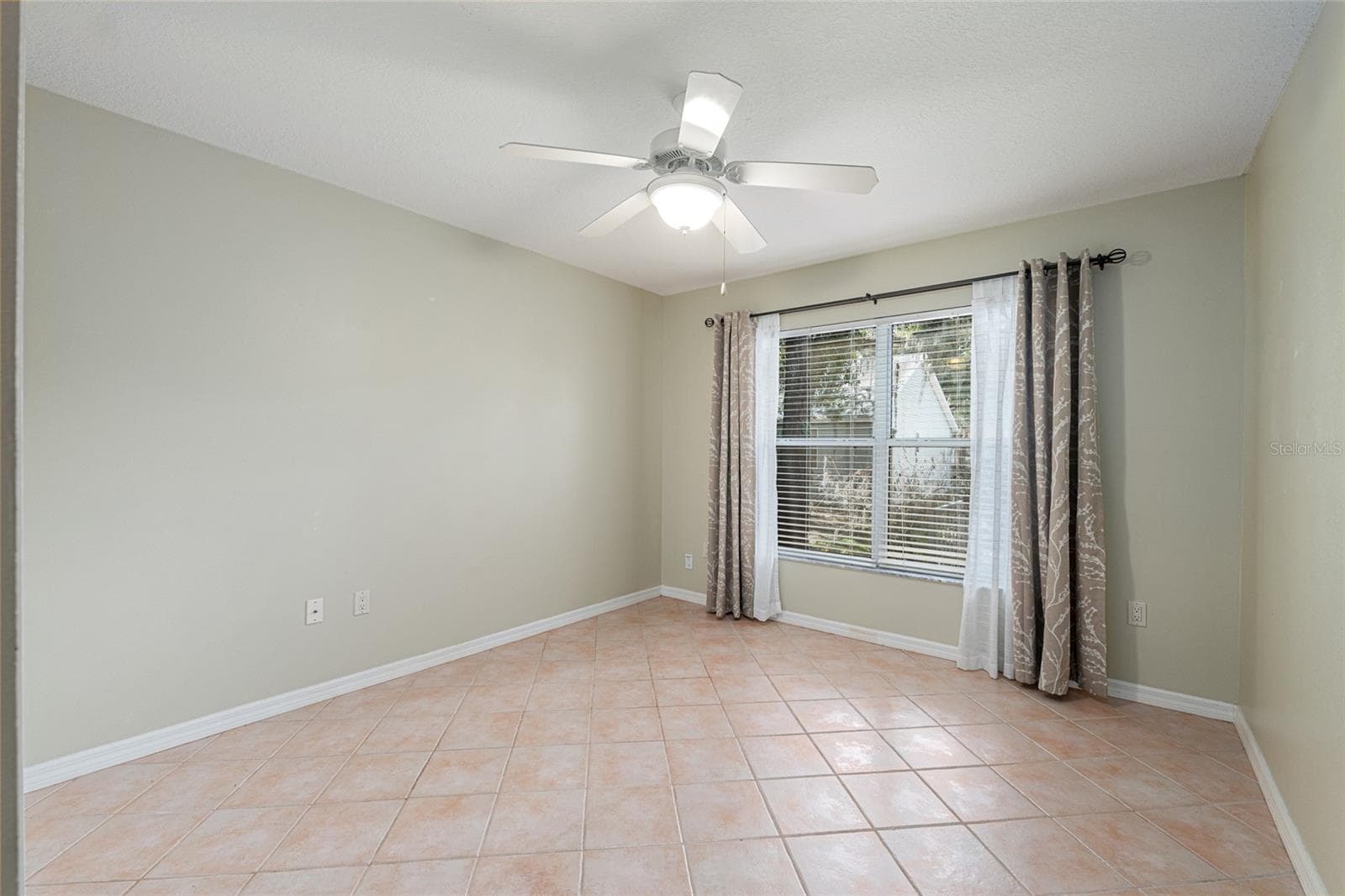 Secondary Bedroom (Alternate View): Additional bedroom offers a spacious layout with tile flooring and a large window for natural light. - 110 CHULA VISTA AVE, LADY LAKE