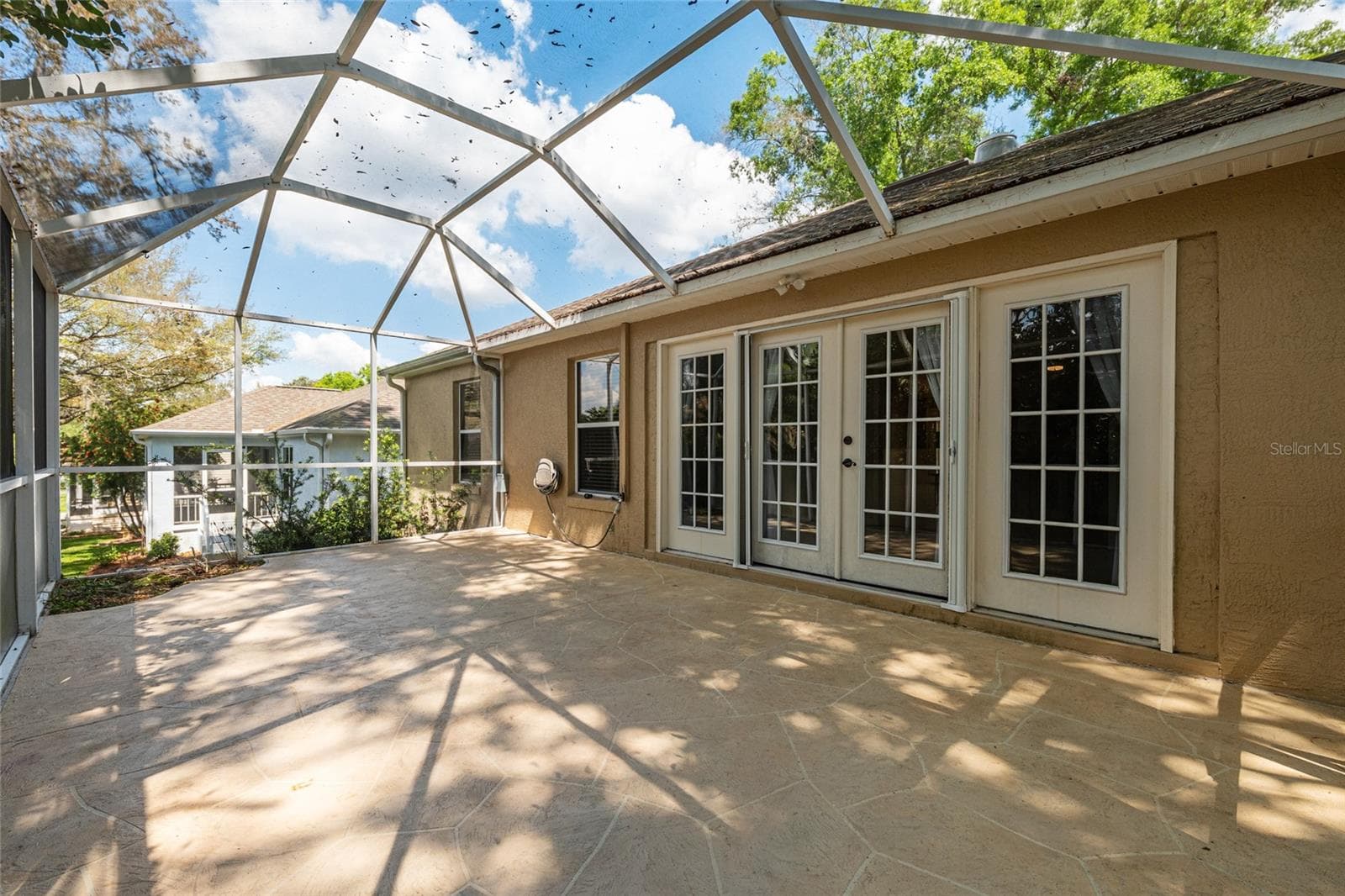 Screened Patio (Alternate View): Screened patio offers a spacious layout with multiple access points and views of surrounding greenery. - 110 CHULA VISTA AVE, LADY LAKE