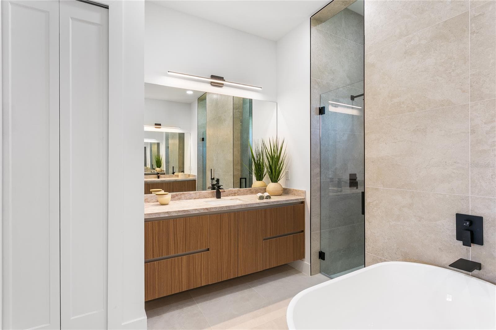 Primary spa bathroom with stand-alone tub, dual sinks, floating cabinetry and marble countertops! - 3300 NW 1ST TER, CAPE CORAL