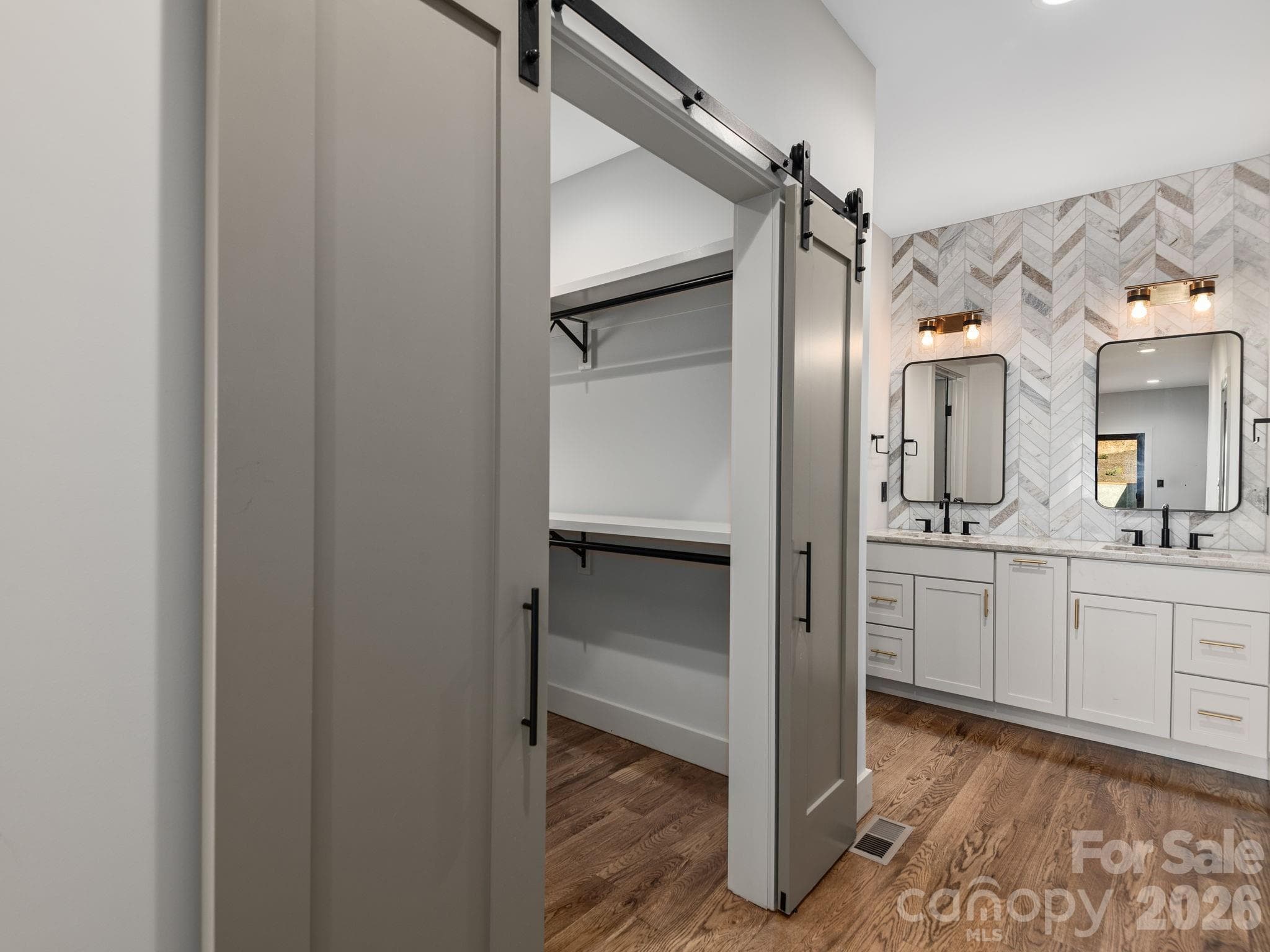 Representative photo from 50 Verde Drive showing the builder’s quality of construction and finish level, including a primary ensuite with spacious walk-in closet, wood shelving, sliding barn doors, Wolf cabinetry, granite countertops, and a designer tiled accent wall. - Asheville