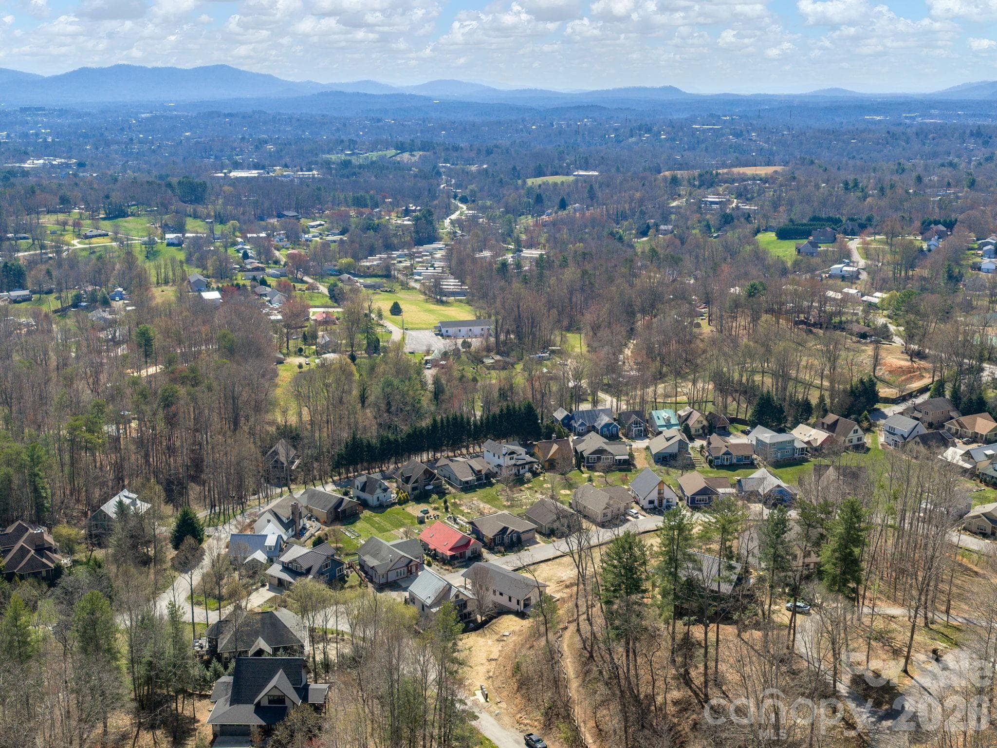 Aerial drone view of The Villages at Crest Mountain and surrounding area, showcasing the community setting and regional mountain backdrop. - Asheville