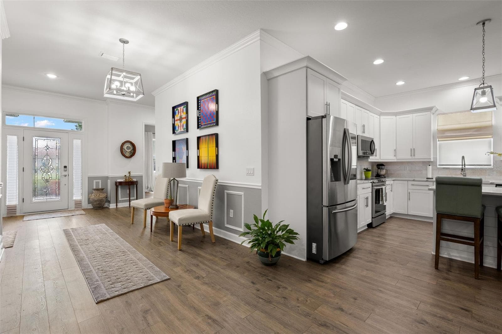 The oversized foyer makes an immediate impression with wide-plank luxury vinyl flooring, extensive crown molding, wainscoting, chair rail detailing, recessed lighting, and an elegant leaded glass entry door with sidelights. - 1720 VERDE DR, CLEARWATER