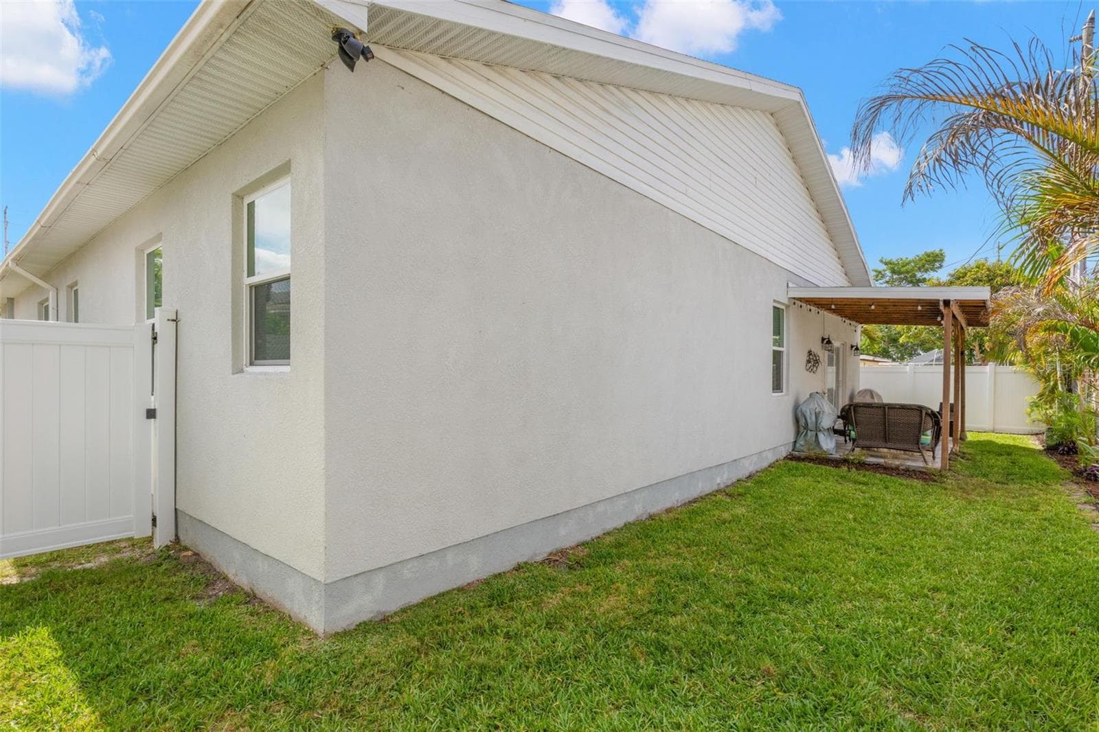The fully fenced backyard offers privacy, low-maintenance landscaping, and ample green space surrounding the covered rear patio. Rain gutters, impact windows, and durable block construction contribute to the home’s thoughtful exterior design and functionality. - 1720 VERDE DR, CLEARWATER
