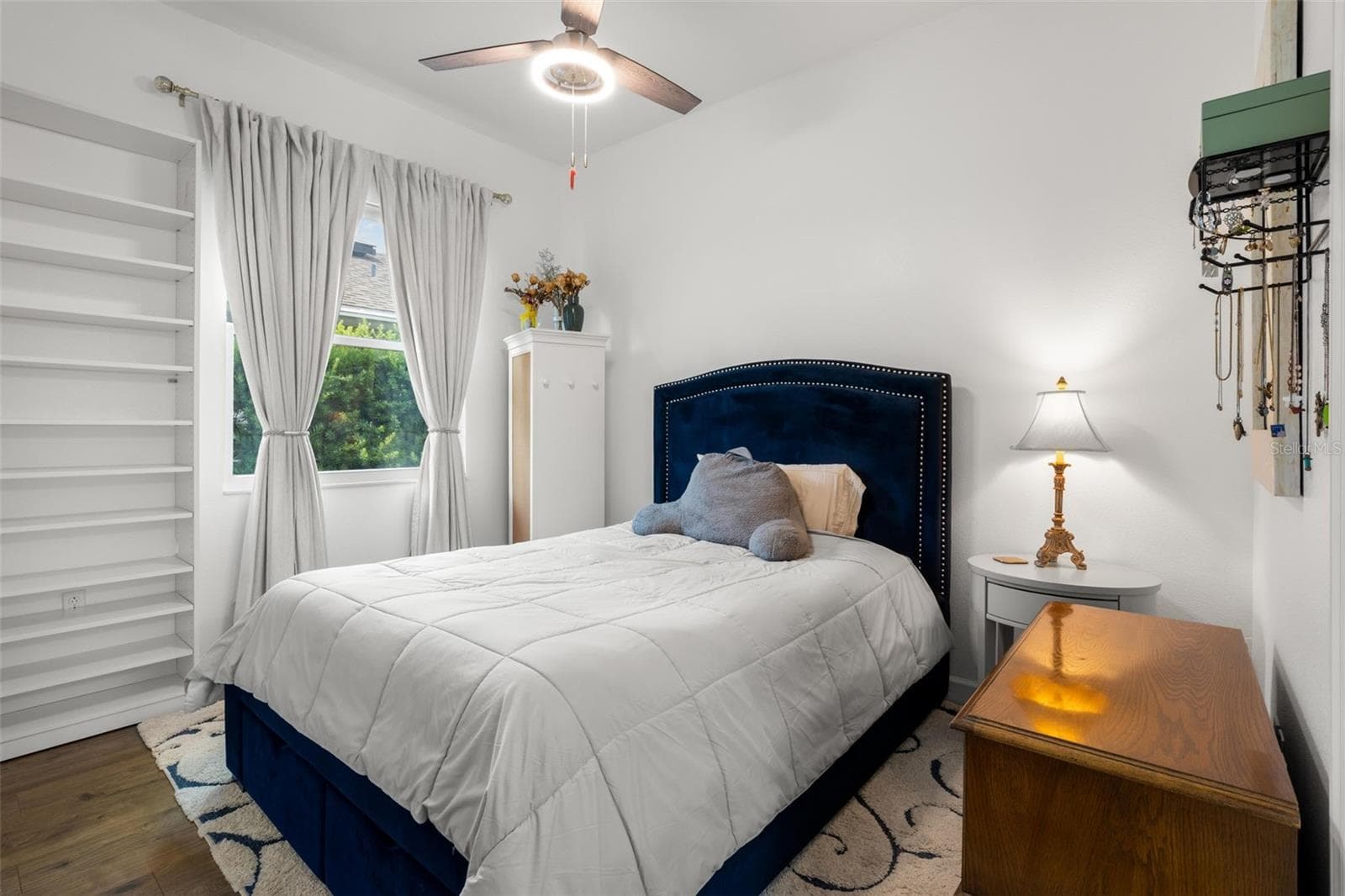 Bedroom 3 features wide-plank luxury vinyl flooring, neutral finishes, built-in shelving, ensuite bathroom and a contemporary ceiling fan. - 1720 VERDE DR, CLEARWATER