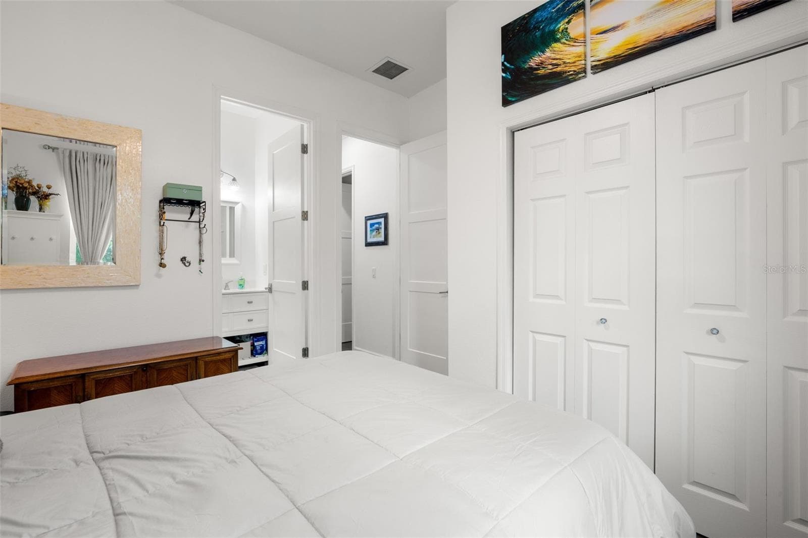 Bedroom 3 features wide-plank luxury vinyl flooring, abundant natural light, neutral finishes, a contemporary ceiling fan, and built-in shelving for additional display and storage space. The room also includes oversized paneled doors and convenient access to the ensuite full bath. - 1720 VERDE DR, CLEARWATER