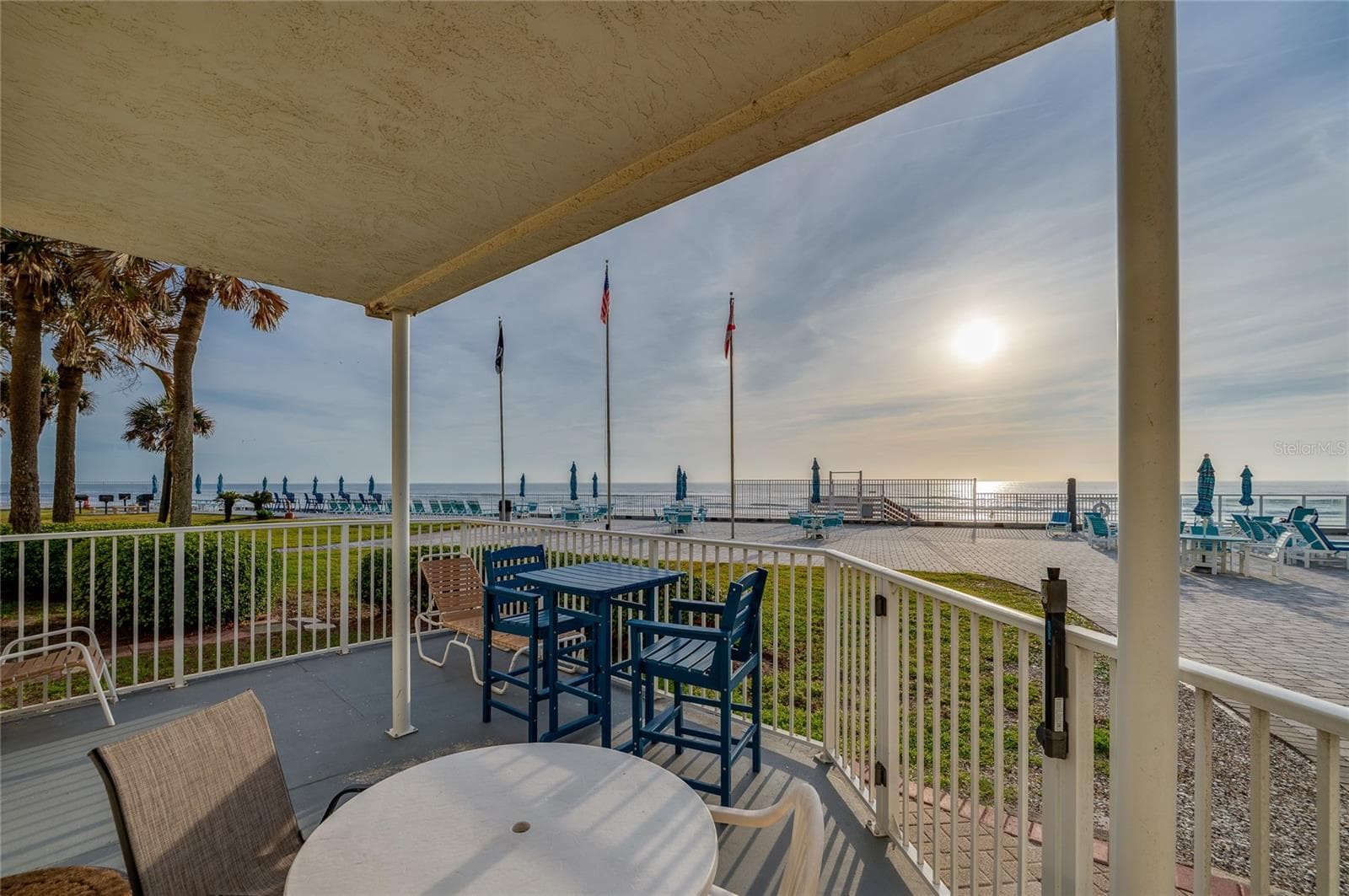 Spacious covered patio featuring versatile seating options, including a high-top bistro set and lounge chair. - 935 S ATLANTIC AVE #165, DAYTONA BEACH